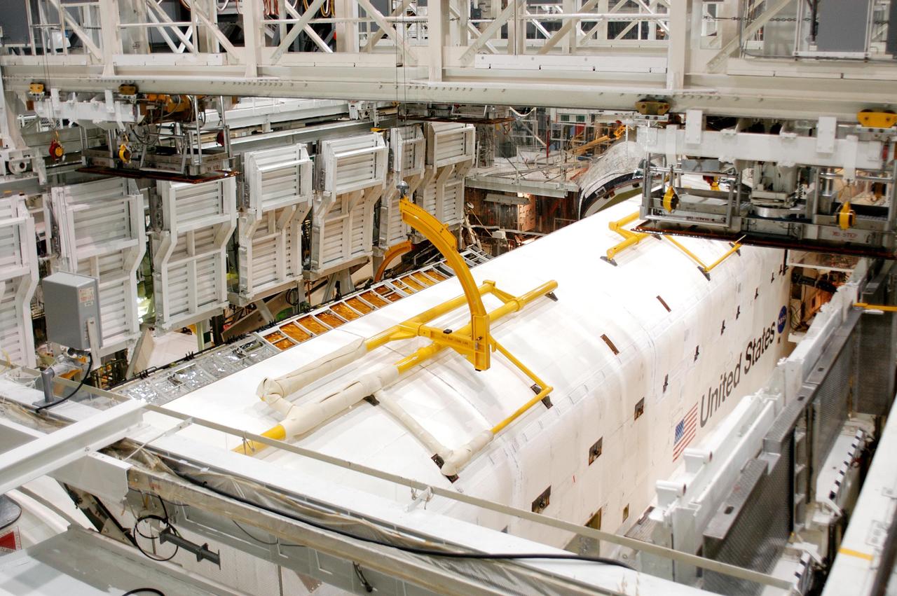 KENNEDY SPACE CENTER, FLA. -  In the Orbiter Processing Facility, the payload bay doors on Atlantis are being closed in preparation for the expected impact of Hurricane Frances on Saturday. Other preparations at KSC include powering down the Space Shuttle orbiters and stowing the landing gear.  Workers are also taking precautions against flooding by moving spacecraft hardware off the ground and sandbagging facilities. The Orbiter Processing Facility is constructed of concrete and steel and was designed to withstand winds of 105 mph.  The Vehicle Assembly Building is constructed of concrete and steel and was designed to withstand winds of 125 mph. Other payload and flight hardware support facilities can endure winds of 110 mph.  Launch pads and the Payload Hazardous Servicing Facility can withstand 125-mph winds.