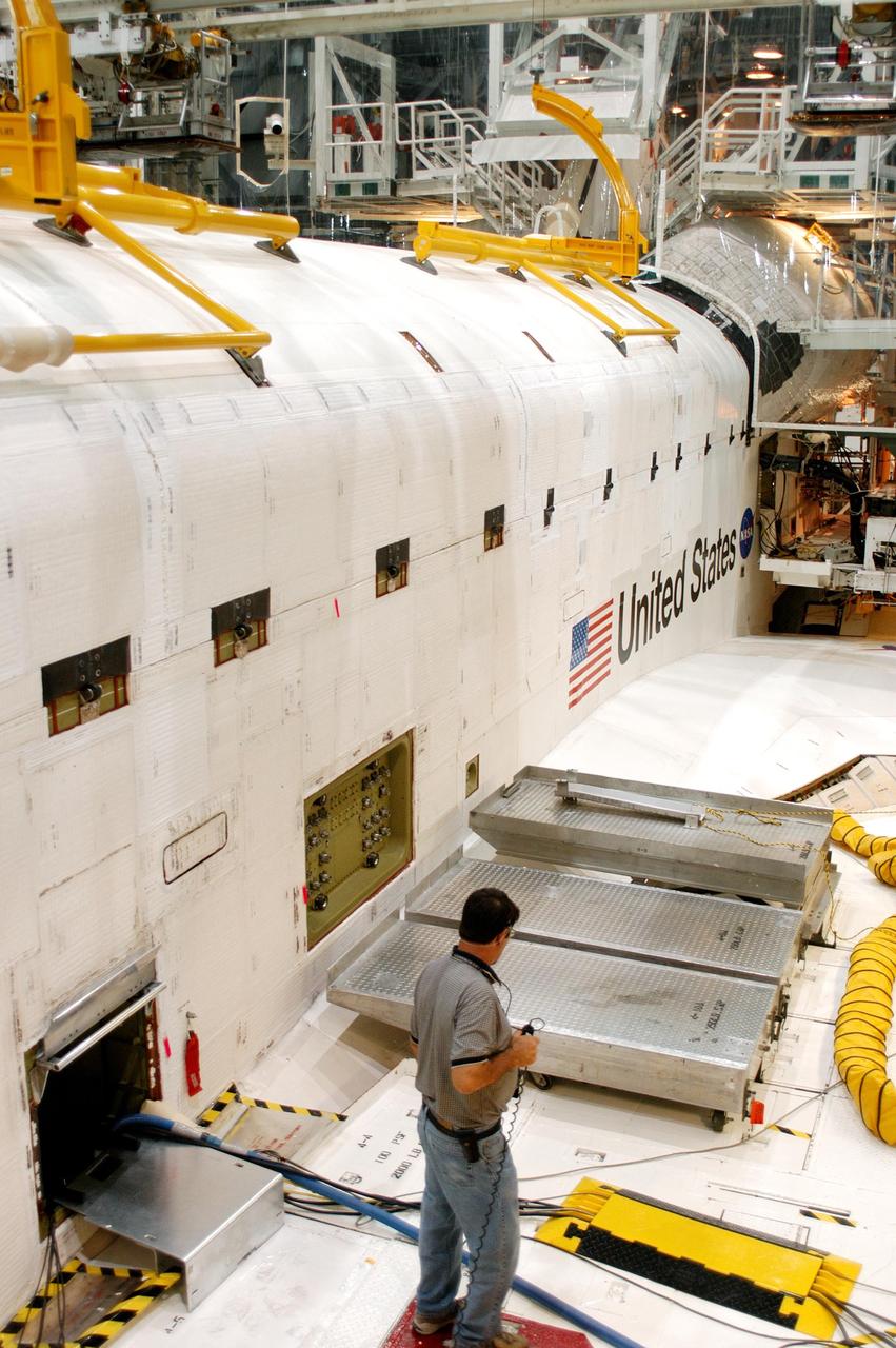 KENNEDY SPACE CENTER, FLA. -  In the Orbiter Processing Facility, a worker checks out part of Atlantis after payload bay doors were closed in preparation for the expected impact of Hurricane Frances on Saturday. Other preparations at KSC include powering down the Space Shuttle orbiters and stowing the landing gear.  Workers are also taking precautions against flooding by moving spacecraft hardware off the ground and sandbagging facilities. The Orbiter Processing Facility is constructed of concrete and steel and was designed to withstand winds of 105 mph.  The Vehicle Assembly Building is constructed of concrete and steel and was designed to withstand winds of 125 mph. Other payload and flight hardware support facilities can endure winds of 110 mph.  Launch pads and the Payload Hazardous Servicing Facility can withstand 125-mph winds.
