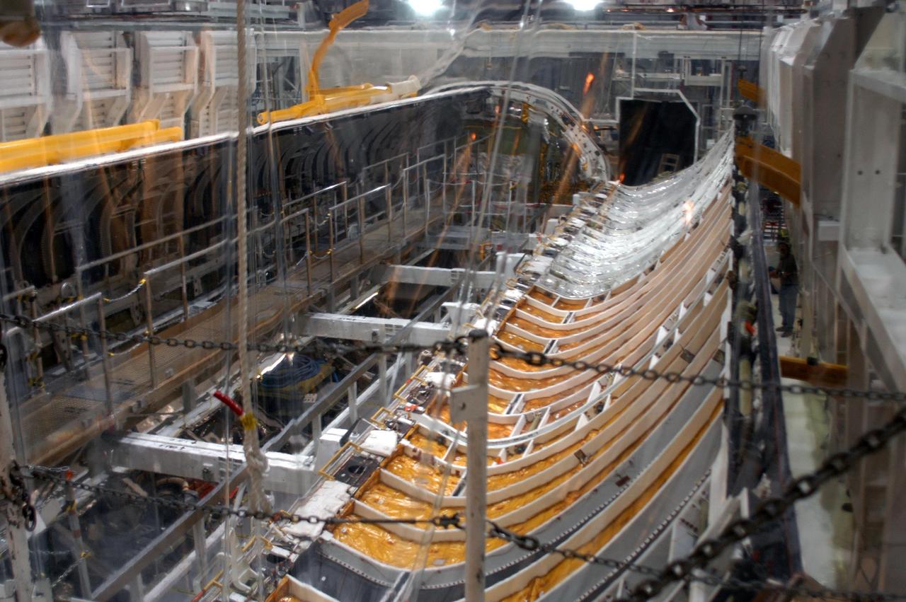 KENNEDY SPACE CENTER, FLA. -  In the Orbiter Processing Facility, the payload bay doors on Atlantis are being closed in preparation for the expected impact of Hurricane Frances on Saturday. Other preparations at KSC include powering down the Space Shuttle orbiters and stowing the landing gear.  Workers are also taking precautions against flooding by moving spacecraft hardware off the ground and sandbagging facilities. The Orbiter Processing Facility is constructed of concrete and steel and was designed to withstand winds of 105 mph.  The Vehicle Assembly Building is constructed of concrete and steel and was designed to withstand winds of 125 mph. Other payload and flight hardware support facilities can endure winds of 110 mph.  Launch pads and the Payload Hazardous Servicing Facility can withstand 125-mph winds.