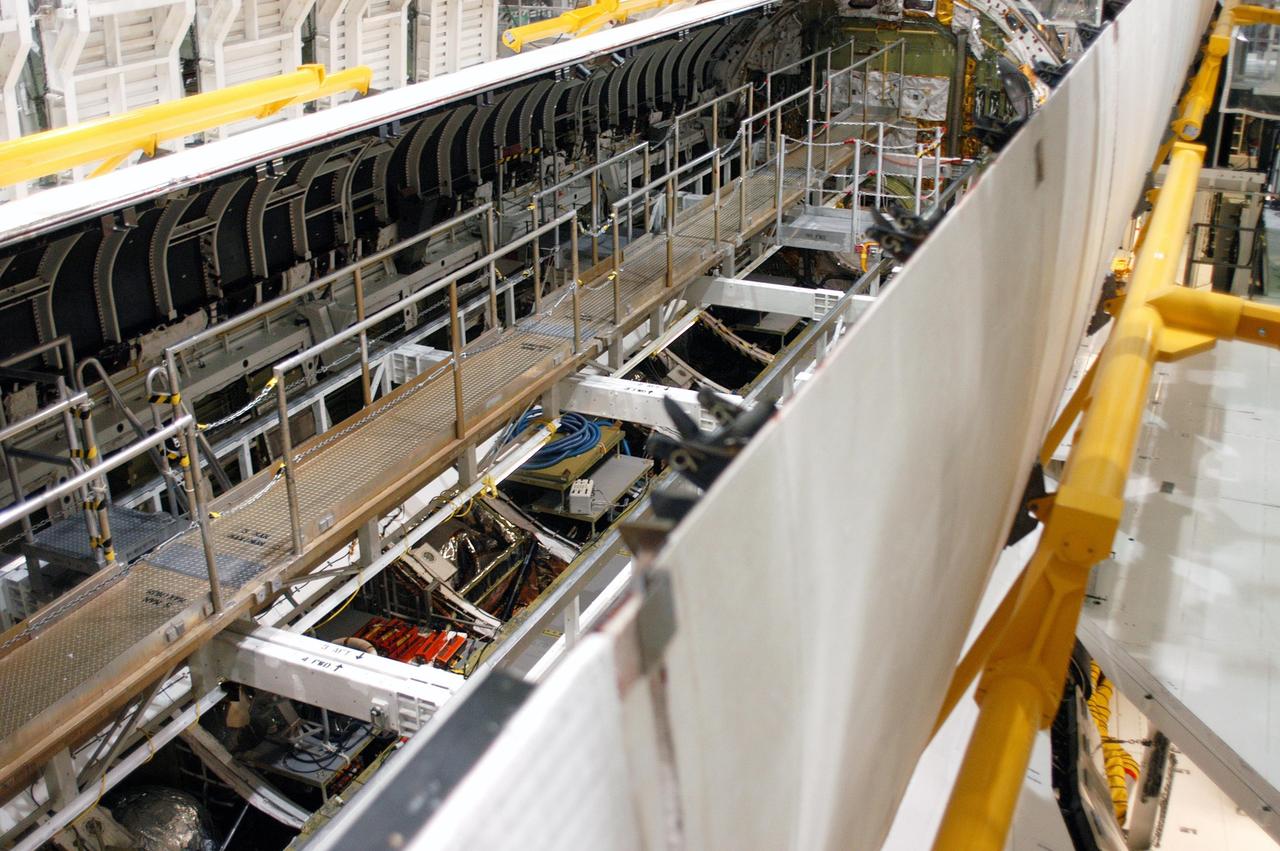 KENNEDY SPACE CENTER, FLA. -  In the Orbiter Processing Facility, the payload bay doors on Atlantis are being closed in preparation for the expected impact of Hurricane Frances on Saturday. Other preparations at KSC include powering down the Space Shuttle orbiters and stowing the landing gear.  Workers are also taking precautions against flooding by moving spacecraft hardware off the ground and sandbagging facilities. The Orbiter Processing Facility is constructed of concrete and steel and was designed to withstand winds of 105 mph.  The Vehicle Assembly Building is constructed of concrete and steel and was designed to withstand winds of 125 mph. Other payload and flight hardware support facilities can endure winds of 110 mph.  Launch pads and the Payload Hazardous Servicing Facility can withstand 125-mph winds.