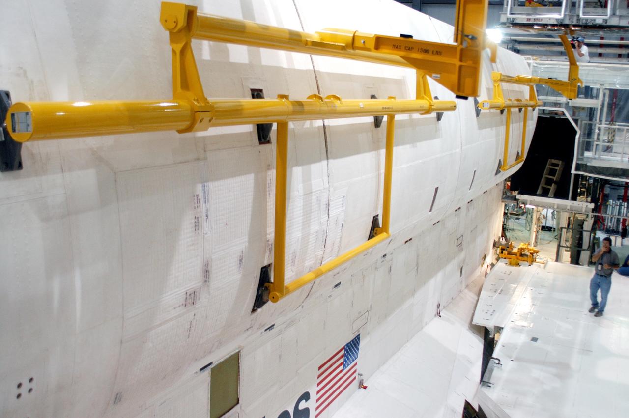 KENNEDY SPACE CENTER, FLA. -  In the Orbiter Processing Facility, the payload bay doors on Atlantis are being closed in preparation for the expected impact of Hurricane Frances on Saturday. Other preparations at KSC include powering down the Space Shuttle orbiters and stowing the landing gear.  Workers are also taking precautions against flooding by moving spacecraft hardware off the ground and sandbagging facilities. The Orbiter Processing Facility is constructed of concrete and steel and was designed to withstand winds of 105 mph.  The Vehicle Assembly Building is constructed of concrete and steel and was designed to withstand winds of 125 mph. Other payload and flight hardware support facilities can endure winds of 110 mph.  Launch pads and the Payload Hazardous Servicing Facility can withstand 125-mph winds.
