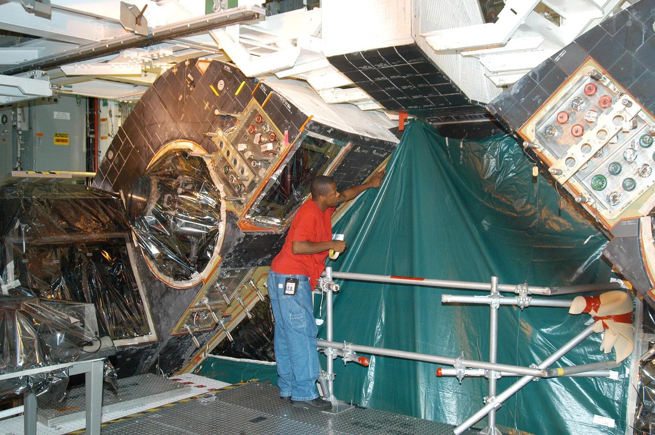 KENNEDY SPACE CENTER, FLA. -  Workers in the Orbiter Processing Facility cover up areas of Atlantis with plastic, preparing for the expected impact of Hurricane Frances on Saturday. Other preparations at KSC include powering down the Space Shuttle orbiters, closing the payload bay doors and stowing the landing gear.  Workers are also taking precautions against flooding by moving spacecraft hardware off the ground and sandbagging facilities. The Orbiter Processing Facility is constructed of concrete and steel and was designed to withstand winds of 105 mph.  The Vehicle Assembly Building is constructed of concrete and steel and was designed to withstand winds of 125 mph. Other payload and flight hardware support facilities can endure winds of 110 mph.  Launch pads and the Payload Hazardous Servicing Facility can withstand 125-mph winds.