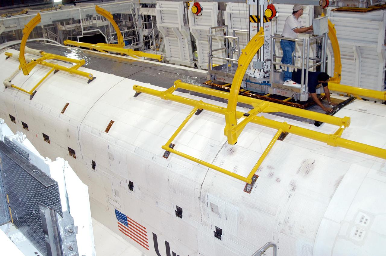 KENNEDY SPACE CENTER, FLA. -  Workers in the Orbiter Processing Facility finish Hurricane preparations on the payload bay doors of Atlantis. Preparing for the expected impact of Hurricane Frances on Saturday, workers also powered down the Space Shuttle orbiters, and stowed the landing gear.  They are also taking precautions against flooding by moving spacecraft hardware off the ground and sandbagging facilities. The Orbiter Processing Facility is constructed of concrete and steel and was designed to withstand winds of 105 mph.  The Vehicle Assembly Building is constructed of concrete and steel and was designed to withstand winds of 125 mph. Other payload and flight hardware support facilities can endure winds of 110 mph.  Launch pads and the Payload Hazardous Servicing Facility can withstand 125-mph winds.
