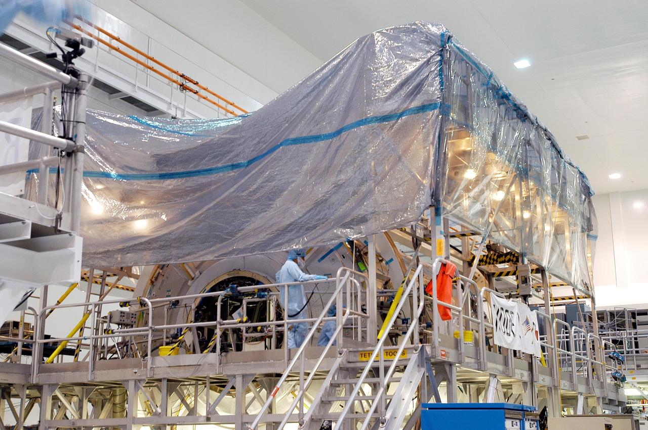 KENNEDY SPACE CENTER, FLA. -  In the Space Station Processing Facility, workers cover with plastic the U.S. Node 2 in preparation for the expected impact of Hurricane Frances on Saturday.  Other modules and equipment are being covered as well.  Workers also have powered down the Space Shuttle orbiters, closed their payload bay doors and stowed the landing gear.  They are also taking precautions against flooding by moving spacecraft hardware off the ground and sandbagging facilities. The SSPF can withstand sustained winds of 110 mph and wind gusts up to 132 mph.  The Orbiter Processing Facility is constructed of concrete and steel and was designed to withstand winds of 105 mph.  The Vehicle Assembly Building is constructed of concrete and steel and was designed to withstand winds of 125 mph. Other payload and flight hardware support facilities can endure winds of 110 mph.  Launch pads and the Payload Hazardous Servicing Facility can withstand 125-mph winds.