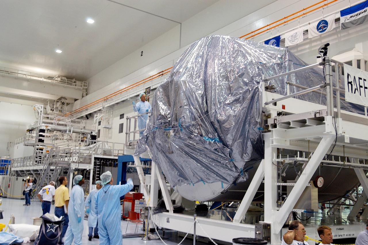 KENNEDY SPACE CENTER, FLA. -  In the Space Station Processing Facility, workers cover with plastic the Multi-Purpose Logistics Module Raffaello in preparation for the expected impact of Hurricane Frances on Saturday.  Other modules and equipment are being covered as well.  Workers also have powered down the Space Shuttle orbiters, closed their payload bay doors and stowed the landing gear.  They are also taking precautions against flooding by moving spacecraft hardware off the ground and sandbagging facilities. The SSPF can withstand sustained winds of 110 mph and wind gusts up to 132 mph.  The Orbiter Processing Facility is constructed of concrete and steel and was designed to withstand winds of 105 mph.  The Vehicle Assembly Building is constructed of concrete and steel and was designed to withstand winds of 125 mph. Other payload and flight hardware support facilities can endure winds of 110 mph.  Launch pads and the Payload Hazardous Servicing Facility can withstand 125-mph winds.