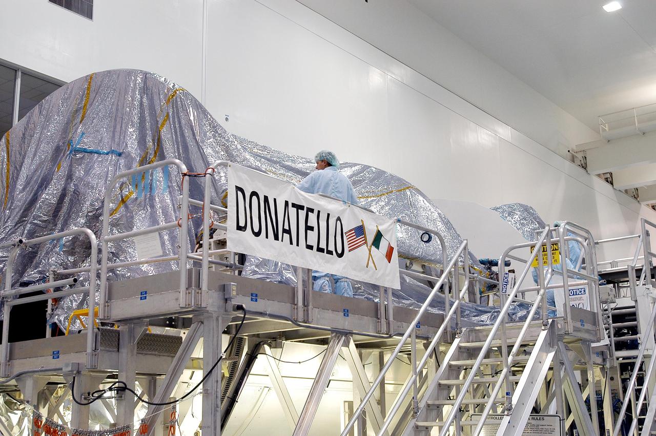 KENNEDY SPACE CENTER, FLA. -  In the Space Station Processing Facility, workers cover with plastic the Multi-Purpose Logistics Module Donatello in preparation for the expected impact of Hurricane Frances on Saturday.  Other modules and equipment are being covered as well.  Workers also have powered down the Space Shuttle orbiters, closed their payload bay doors and stowed the landing gear.  They are also taking precautions against flooding by moving spacecraft hardware off the ground and sandbagging facilities. The SSPF can withstand sustained winds of 110 mph and wind gusts up to 132 mph.  The Orbiter Processing Facility is constructed of concrete and steel and was designed to withstand winds of 105 mph.  The Vehicle Assembly Building is constructed of concrete and steel and was designed to withstand winds of 125 mph. Other payload and flight hardware support facilities can endure winds of 110 mph.  Launch pads and the Payload Hazardous Servicing Facility can withstand 125-mph winds.