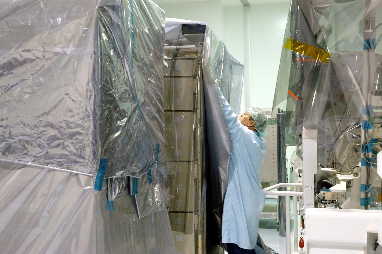 KENNEDY SPACE CENTER, FLA. -  In the Space Station Processing Facility, a worker wraps equipment in plastic in preparation for the expected impact of Hurricane Frances on Saturday. The various modules in the SSPF, such as the Japanese Experiment Module, U.S. Node 2 and Multi-Purpose Logistics Modules, are being covered as well. KSC workers also have powered down the Space Shuttle orbiters, closed their payload bay doors and stowed the landing gear.  They are also taking precautions against flooding by moving spacecraft hardware off the ground and sandbagging facilities. The SSPF can withstand sustained winds of 110 mph and wind gusts up to 132 mph.  The Orbiter Processing Facility is constructed of concrete and steel and was designed to withstand winds of 105 mph.  The Vehicle Assembly Building is constructed of concrete and steel and was designed to withstand winds of 125 mph. Other payload and flight hardware support facilities can endure winds of 110 mph.  Launch pads and the Payload Hazardous Servicing Facility can withstand 125-mph winds.