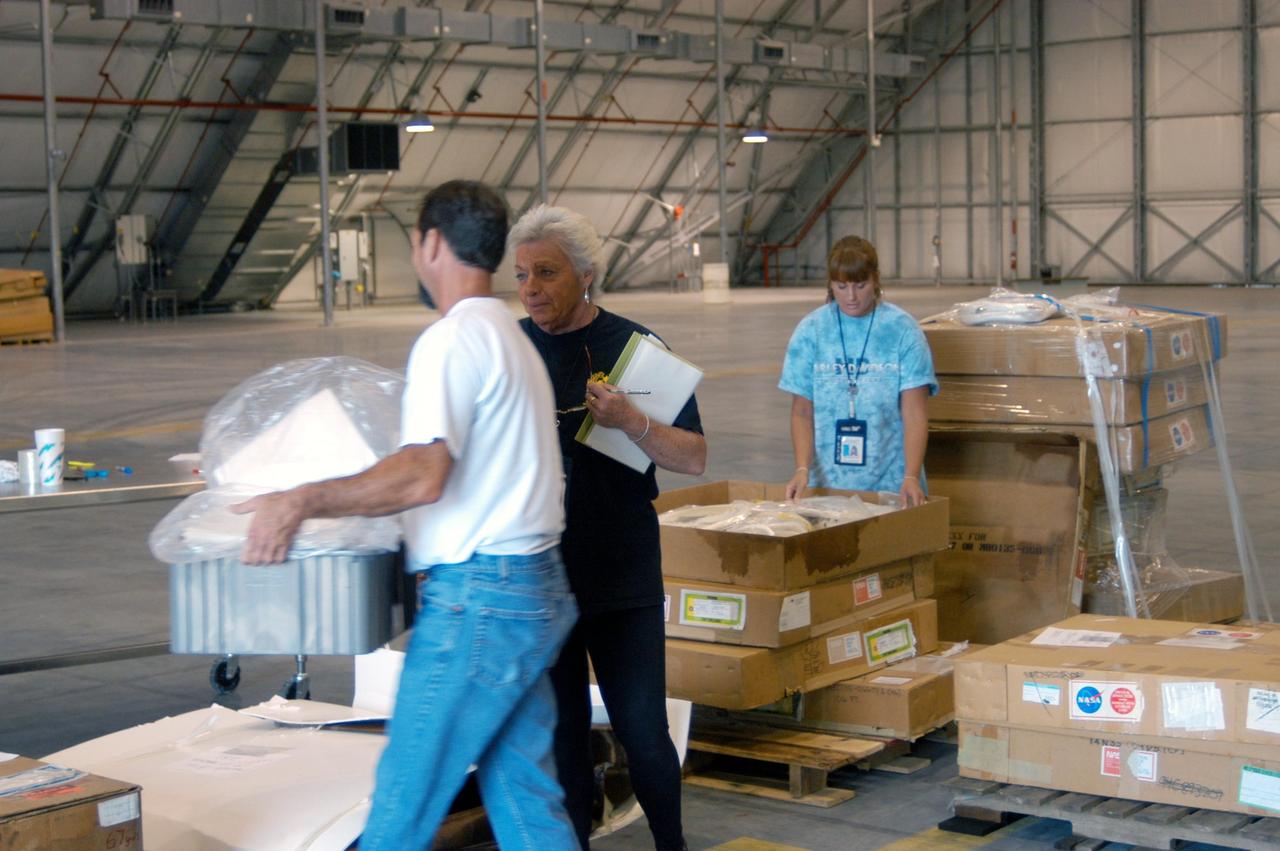 KENNEDY SPACE CENTER, FLA. -   KSC employees move equipment from the Thermal Protection System Facility (TPSF), damaged by Hurricane Frances, into a hangar and storage facility near the KSC Shuttle Landing Facility. Previously, this hangar was used to house the Space Shuttle Columbia debris. Located in Launch Complex 39, the TPSF is used to manufacture both internal and external insulation products for the Space Shuttle orbiters.  The storm's path over Florida took it through Cape Canaveral and KSC property during Labor Day weekend.