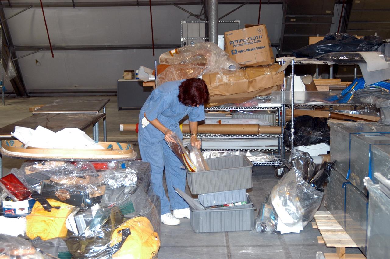 KENNEDY SPACE CENTER, FLA. -   A KSC employee unpacks and sorts equipment moved from the Thermal Protection System Facility (TPSF), damaged by Hurricane Frances, to a hangar and storage facility near the KSC Shuttle Landing Facility. Previously, this hangar was used to house the Space Shuttle Columbia debris. Located in Launch Complex 39, the TPSF is used to manufacture both internal and external insulation products for the Space Shuttle orbiters.  The storm's path over Florida took it through Cape Canaveral and KSC property during Labor Day weekend.