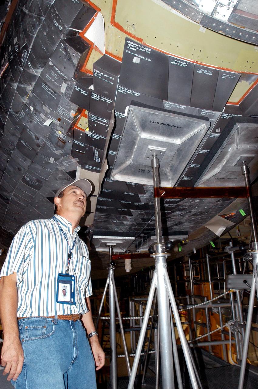 KENNEDY SPACE CENTER, FLA. - United Space Alliance employee Dan Coleman inspects Space Shuttle Discovery in the Orbiter Processing Facility following Hurricane Frances. The storm's path over Florida took it through Cape Canaveral and KSC property during Labor Day weekend. There was no damage to the Space Shuttle orbiters or to any other flight hardware.