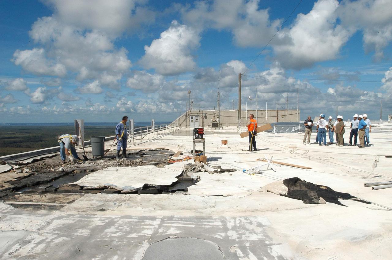 KENNEDY SPACE CENTER, FLA. -   Members of a hurricane assessment team from Johnson Space Center and Marshall Space Flight Center look at damage on the roof of the Vehicle Assembly Building  (VAB) a week after Hurricane Frances hit the east coast of Central Florida and Kennedy Space Center.  The VAB lost 820, 4- x 16-foot panels from the side walls, or more than 52,000 square feet of its surface.