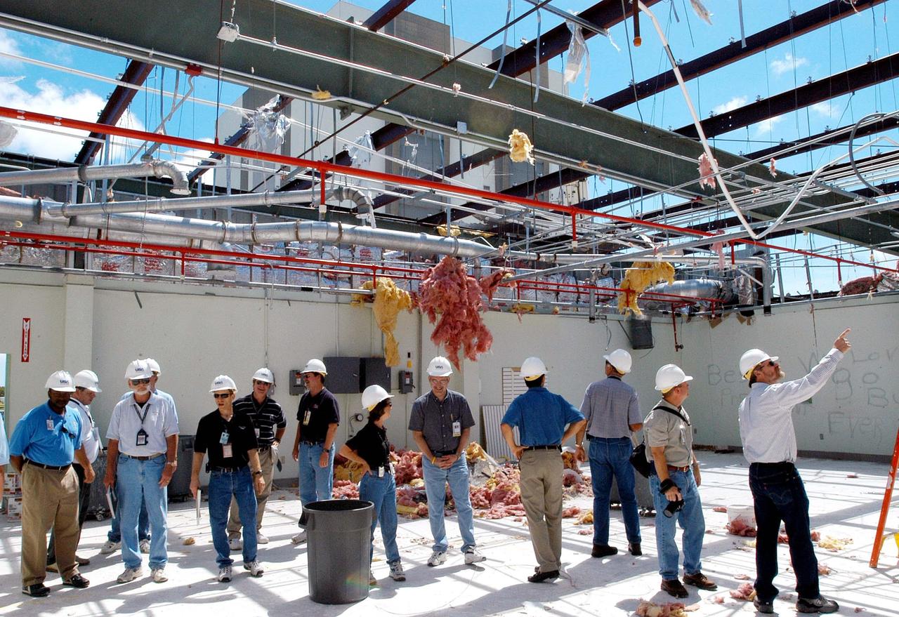 KENNEDY SPACE CENTER, FLA. -  Members of a hurricane assessment team from Johnson Space Center and Marshall Space Flight Center observe the damage to the roof of the Thermal Protection System (TPS) Facility at KSC after Hurricane Frances hit the east coast of Central Florida and Kennedy Space Center. The facility, which creates the TPS tiles, blankets and all the internal thermal control systems for the Space Shuttles, is almost totally unserviceable at this time after losing approximately 35 percent of its roof.  Equipment and materials that survived the storm have been relocated to the RLV hangar near the KSC Shuttle Landing Facility.