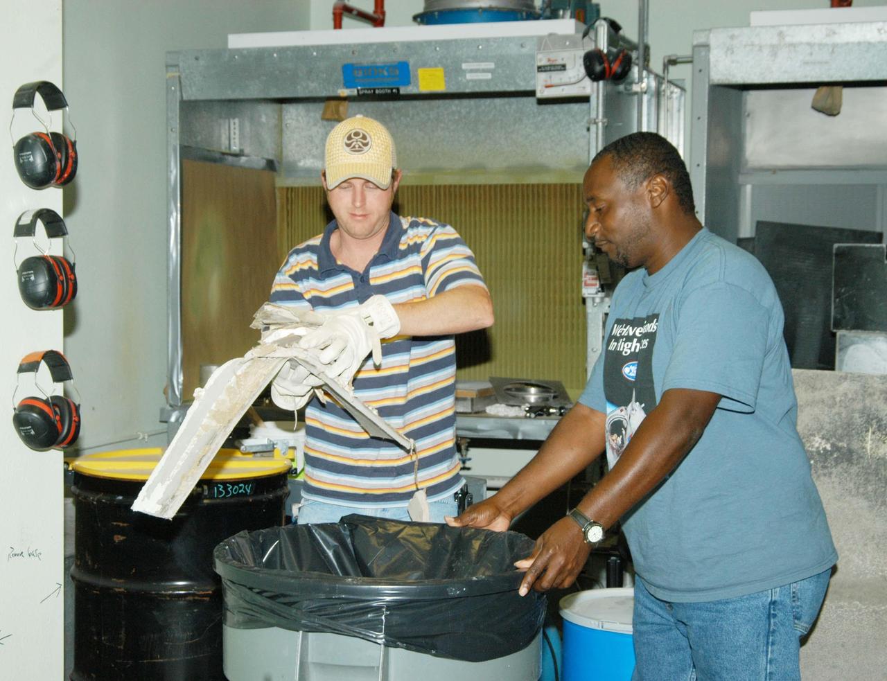 KENNEDY SPACE CENTER, FLA. -  United Space Alliance workers Dallas Lewis (left) and Damon Petty clean up hurricane debris inside the Thermal Protection System Facility (TPSF).  Much of the roof was torn off by Hurricane Frances as it passed over Central Florida during the Labor Day weekend.  Undamaged equipment has been moved to the RLV hangar at KSC.  The TPSF, which creates the TPS tiles, blankets and all the internal thermal control systems for the Space Shuttles, is almost totally unserviceable at this time after losing approximately 35 percent of its roof.  The maximum wind at the surface from Hurricane Frances was 94 mph from the northeast at 6:40 a.m. on Sunday, September 5.  It was recorded at a weather tower located on the east shore of the Mosquito Lagoon near the Cape Canaveral National Seashore.  The highest sustained wind at KSC was 68 mph.