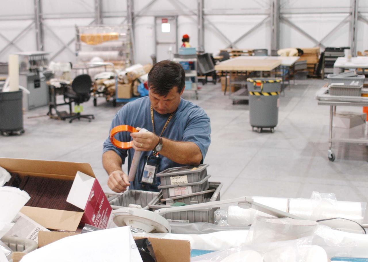 KENNEDY SPACE CENTER, FLA. -  In the RLV hangar at KSC, United Space Alliance worker Steve Mitchell unpacks equipment that was removed from the hurricane-ravaged Thermal Protection System Facility (TPSF).  The facility, which creates the TPS tiles, blankets and all the internal thermal control systems for the Space Shuttles, is almost totally unserviceable at this time after losing approximately 35 percent of its roof due to Hurricane Frances, which blew across Central Florida Sept. 4-5.  The maximum wind at the surface from Hurricane Frances was 94 mph from the northeast at 6:40 a.m. on Sunday, September 5.  It was recorded at a weather tower located on the east shore of the Mosquito Lagoon near the Cape Canaveral National Seashore.  The highest sustained wind at KSC was 68 mph.
