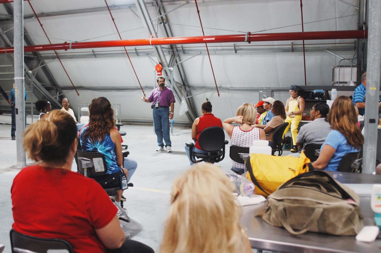 KENNEDY SPACE CENTER, FLA. -   In the RLV hangar at KSC, Steve Harrington talks to workers about the equipment removed from the hurricane-ravaged Thermal Protection System Facility (TPSF) now being stored in the hangar.  The facility, which creates the TPS tiles, blankets and all the internal thermal control systems for the Space Shuttles, is almost totally unserviceable at this time after losing approximately 35 percent of its roof due to Hurricane Frances, which blew across Central Florida Sept. 4-5.  The maximum wind at the surface from Hurricane Frances was 94 mph from the northeast at 6:40 a.m. on Sunday, September 5.  It was recorded at a weather tower located on the east shore of the Mosquito Lagoon near the Cape Canaveral National Seashore.  The highest sustained wind at KSC was 68 mph.