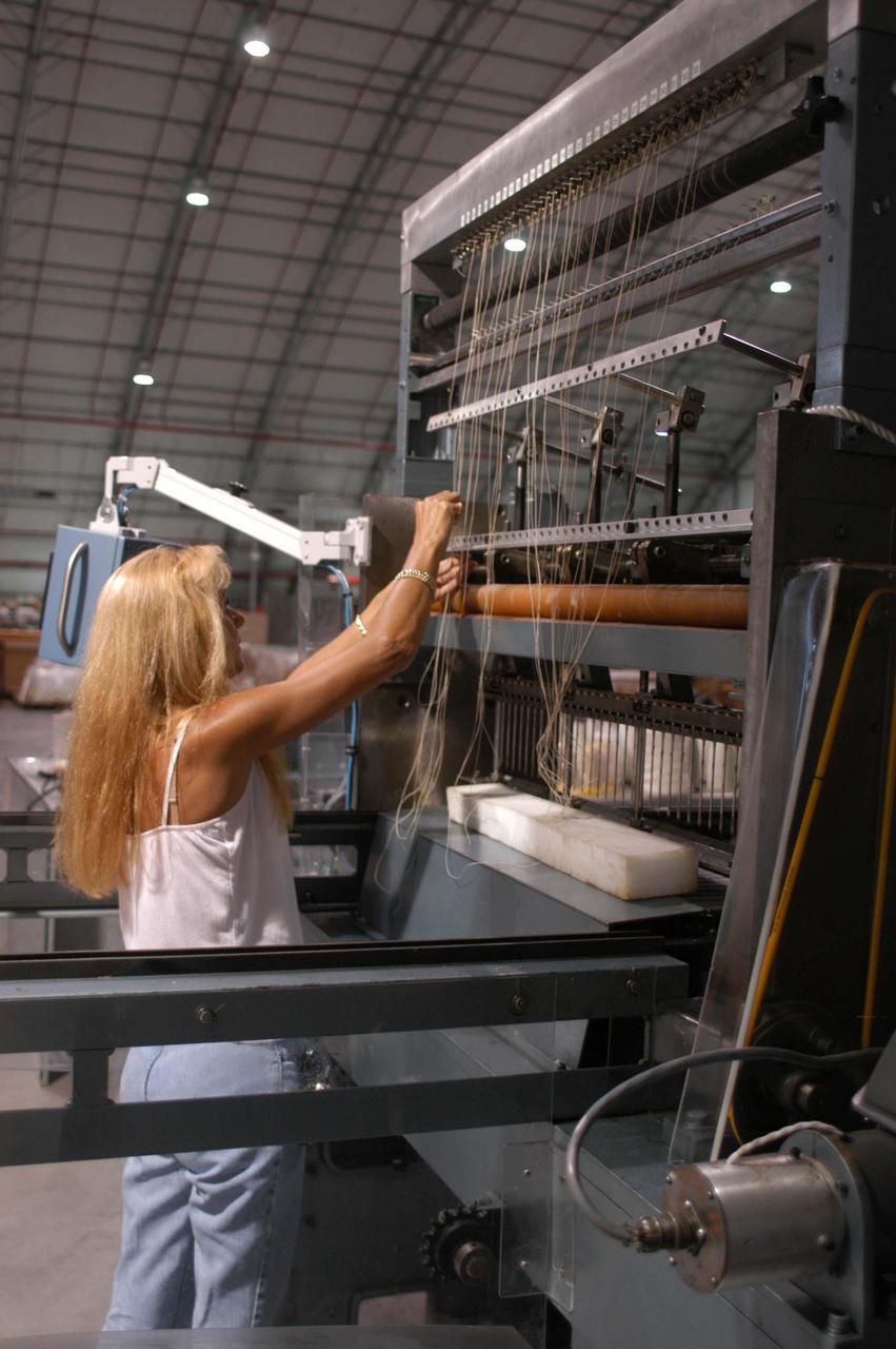 KENNEDY SPACE CENTER, FLA. -  United Space Alliance worker Bab Jarosz works with the 30-needle sewing machines from the Thermal Protection System Facility (TPSF).  A temporary tile shop has been set up in the RLV hangar at KSC after equipment was removed from the hurricane-ravaged facility.  The TPSF,  which creates the TPS tiles, blankets and all the internal thermal control systems for the Space Shuttles, is almost totally unserviceable at this time after losing approximately 35 percent of its roof due to Hurricane Frances, which blew across Central Florida Sept. 4-5.  The maximum wind at the surface from Hurricane Frances was 94 mph from the northeast at 6:40 a.m. on Sunday, September 5.  It was recorded at a weather tower located on the east shore of the Mosquito Lagoon near the Cape Canaveral National Seashore.  The highest sustained wind at KSC was 68 mph.