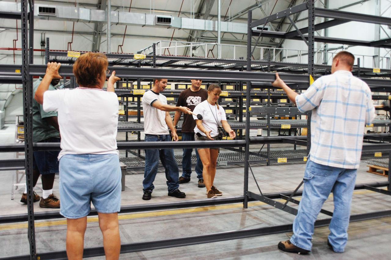 KENNEDY SPACE CENTER, FLA. -  In the RLV hangar at KSC, United Space Alliance workers set up shelves for equipment removed from the hurricane-ravaged Thermal Protection System Facility (TPSF) and now being stored in the hangar.  The facility, which creates the TPS tiles, blankets and all the internal thermal control systems for the Space Shuttles, is almost totally unserviceable at this time after losing approximately 35 percent of its roof due to Hurricane Frances, which blew across Central Florida Sept. 4-5.  The maximum wind at the surface from Hurricane Frances was 94 mph from the northeast at 6:40 a.m. on Sunday, September 5.  It was recorded at a weather tower located on the east shore of the Mosquito Lagoon near the Cape Canaveral National Seashore.  The highest sustained wind at KSC was 68 mph.