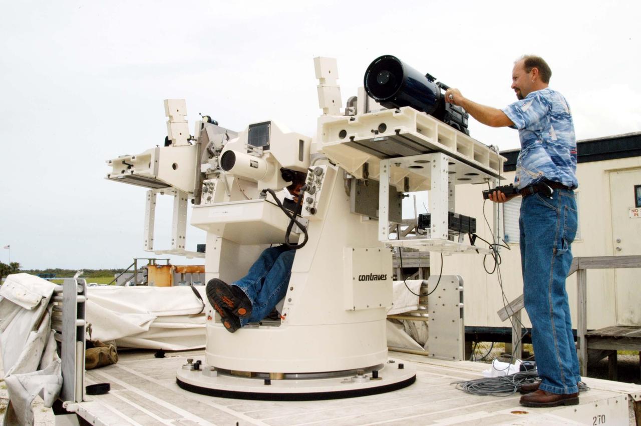 KENNEDY SPACE CENTER, FLA. -  KSC videographer Glenn Benson adjusts a high definition camera  being used to photograph the south wall of the Vehicle Assembly Building that sustained damage from Hurricane Frances as it passed over Central Florida during the Labor Day weekend. The maximum wind at the surface from Hurricane Frances was 94 mph from the northeast at 6:40 a.m. on Sunday, September 5.  It was recorded at a weather tower located on the east shore of the Mosquito Lagoon near the Cape Canaveral National Seashore.  The highest sustained wind at KSC was 68 mph.  The VAB lost 820, 4- x 16-foot panels or more than 52,000 square feet of its surface.  There was damage to the roof as well.