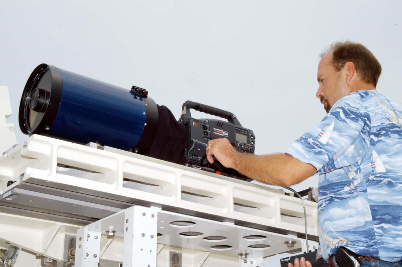 KENNEDY SPACE CENTER, FLA. -  KSC videographer Glenn Benson adjusts a high definition camera being used to photograph the south wall of the Vehicle Assembly Building that sustained damage from Hurricane Frances as it passed over Central Florida during the Labor Day weekend. The maximum wind at the surface from Hurricane Frances was 94 mph from the northeast at 6:40 a.m. on Sunday, September 5.  It was recorded at a weather tower located on the east shore of the Mosquito Lagoon near the Cape Canaveral National Seashore.  The highest sustained wind at KSC was 68 mph.  The VAB lost 820, 4- x 16-foot panels or more than 52,000 square feet of its surface.  There was damage to the roof as well.
