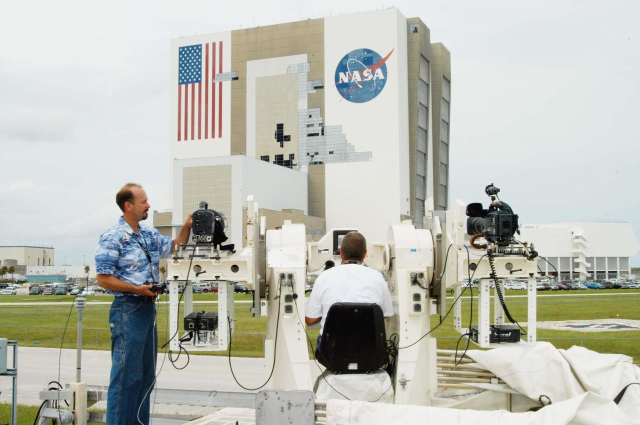KENNEDY SPACE CENTER, FLA. -  KSC videographer Glenn Benson adjusts a high definition camera  being used to photograph the south wall of the Vehicle Assembly Building that sustained damage from Hurricane Frances as it passed over Central Florida during the Labor Day weekend. The maximum wind at the surface from Hurricane Frances was 94 mph from the northeast at 6:40 a.m. on Sunday, September 5.  It was recorded at a weather tower located on the east shore of the Mosquito Lagoon near the Cape Canaveral National Seashore.  The highest sustained wind at KSC was 68 mph.  The VAB lost 820, 4- x 16-foot panels or more than 52,000 square feet of its surface.  There was damage to the roof as well.