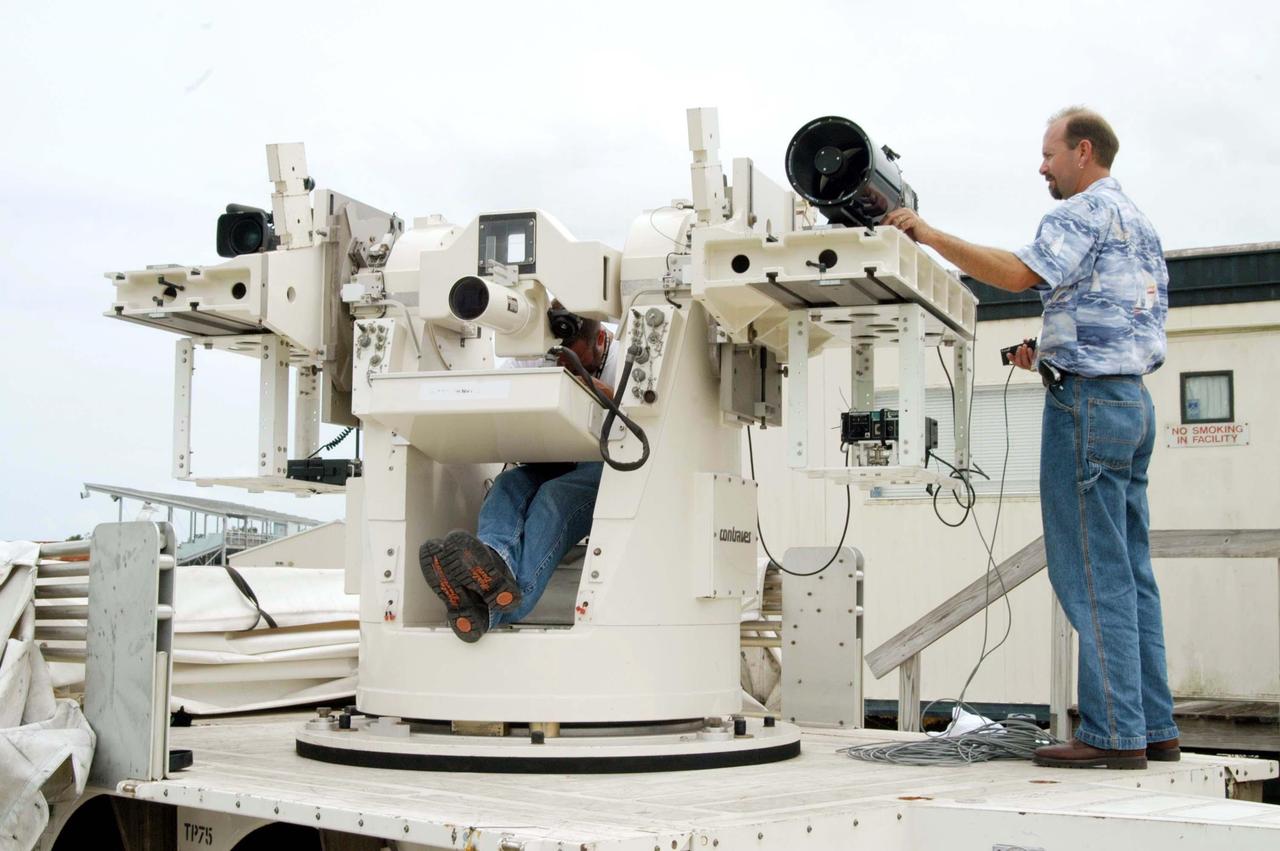 KENNEDY SPACE CENTER, FLA. -  KSC videographer Glenn Benson adjusts a high definition camera  being used to photograph the south wall of the Vehicle Assembly Building (VAB) that sustained damage from Hurricane Frances as it passed over Central Florida during the Labor Day weekend. The maximum wind at the surface from Hurricane Frances was 94 mph from the northeast at 6:40 a.m. on Sunday, September 5.  It was recorded at a weather tower located on the east shore of the Mosquito Lagoon near the Cape Canaveral National Seashore.  The highest sustained wind at KSC was 68 mph.  The VAB lost 820, 4- x 16-foot panels or more than 52,000 square feet of its surface.  There was damage to the roof as well.