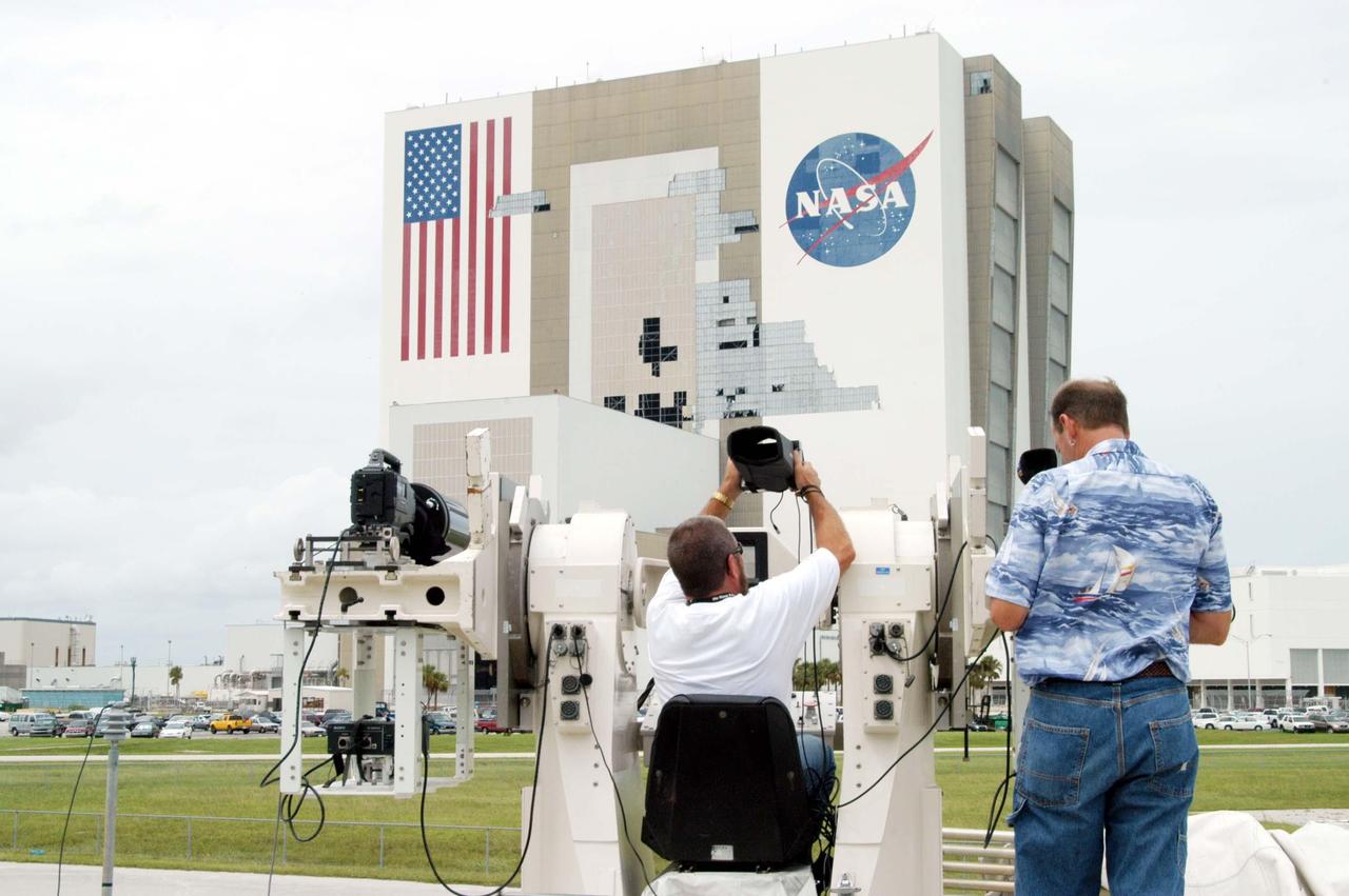 KENNEDY SPACE CENTER, FLA. -  KSC videographer Glenn Benson and photographer Kenny Allen photograph damage incurred on the south wall of the Vehicle Assembly Building (VAB) that sustained damage from Hurricane Frances as it passed over Central Florida during the Labor Day weekend. The maximum wind at the surface from Hurricane Frances was 94 mph from the northeast at 6:40 a.m. on Sunday, September 5.  It was recorded at a weather tower located on the east shore of the Mosquito Lagoon near the Cape Canaveral National Seashore.  The highest sustained wind at KSC was 68 mph.  The VAB lost 820, 4- x 16-foot panels or more than 52,000 square feet of its surface.  There was damage to the roof as well.