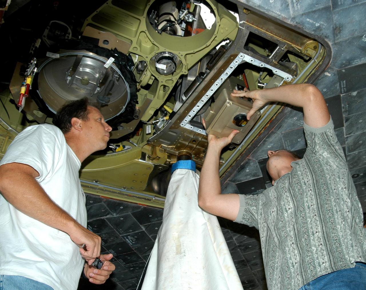 KENNEDY SPACE CENTER, FLA. - In the Orbiter Processing Facility, from left, United Space Alliance workers Loyd Turner, Craig Meyer and Erik Visser conduct a fit check of an External Tank (ET) digital still camera in the right-hand liquid oxygen umbilical well on Space Shuttle Atlantis.  NASA is pursuing use of the camera, beginning with the Shuttle’s Return To Flight, to obtain and downlink high-resolution images of the ET following separation of the ET from the orbiter after launch.  The Kodak camera will record 24 images, at one frame per 1.5 seconds, on a flash memory card.  After orbital insertion, the crew will transfer the images from the memory card to a laptop computer.  The files will then be downloaded through the Ku-band system to the Mission Control Center in Houston for analysis.