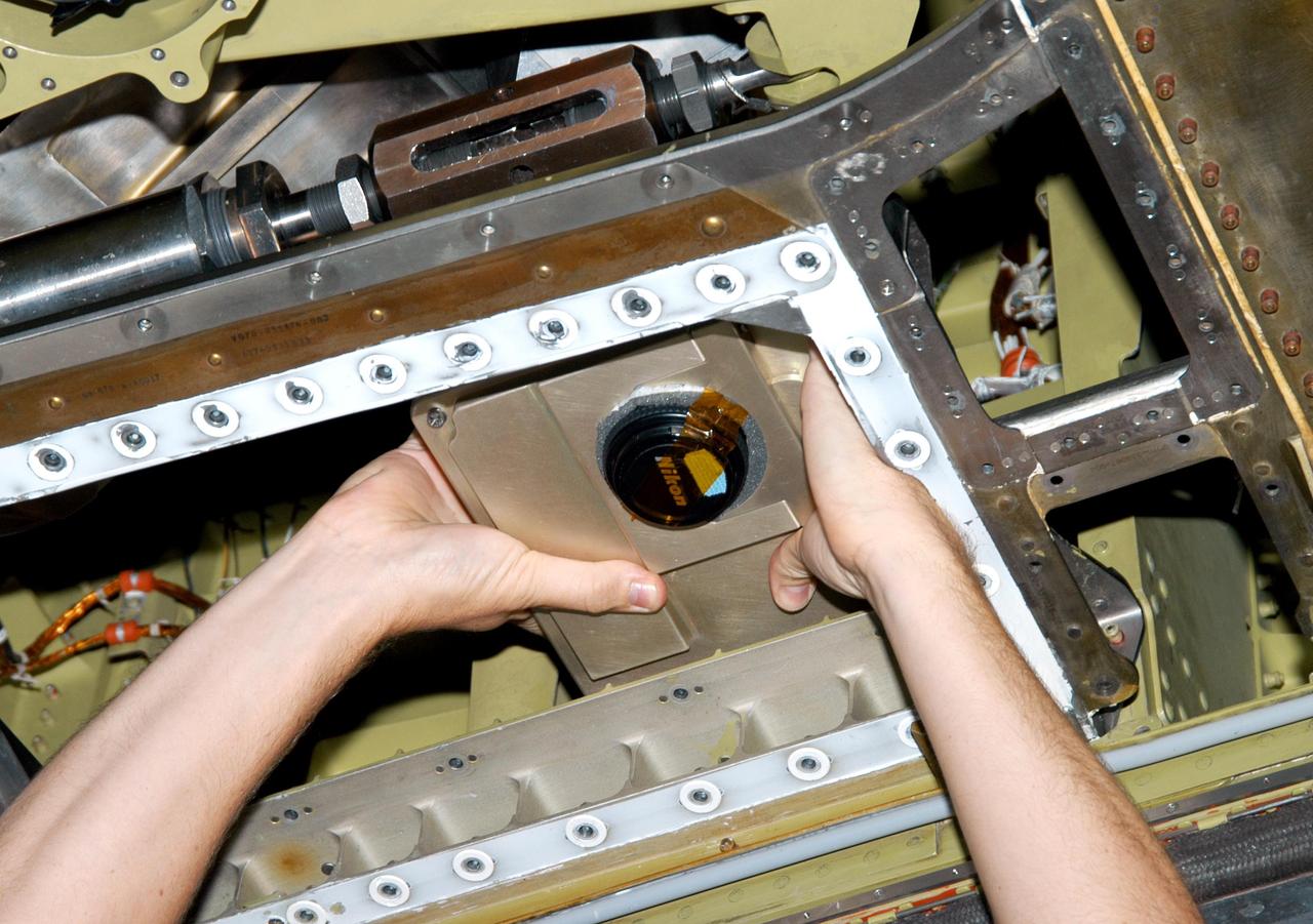 KENNEDY SPACE CENTER, FLA. - In the Orbiter Processing Facility, an External Tank (ET) digital still camera is positioned into the right-hand liquid oxygen umbilical well on Space Shuttle Atlantis to determine if it fits properly. NASA is pursuing use of the camera, beginning with the Shuttle’s Return To Flight, to obtain and downlink high-resolution images of the ET following separation of the ET from the orbiter after launch.  The Kodak camera will record 24 images, at one frame per 1.5 seconds, on a flash memory card.  After orbital insertion, the crew will transfer the images from the memory card to a laptop computer.  The files will then be downloaded through the Ku-band system to the Mission Control Center in Houston for analysis.