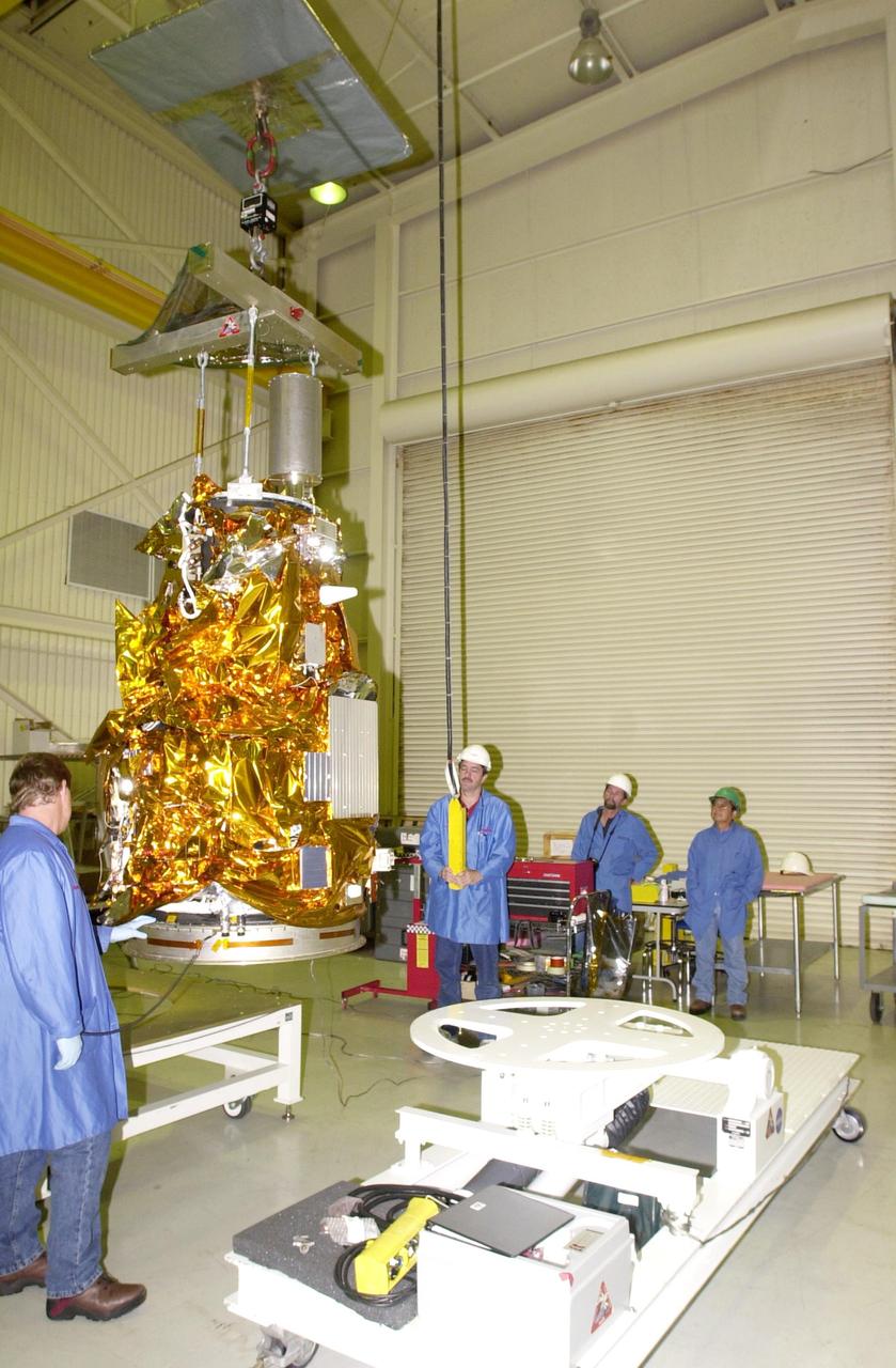KENNEDY SPACE CENTER, FLA. - At Vandenberg Air Force Base in California, workers stand by while an overhead crane moves the Demonstration of Autonomous Rendezvous Technology (DART) spacecraft onto the mobile stand at right. DART was designed and built for NASA by Orbital Sciences Corporation as an advanced flight demonstrator to locate and maneuver near an orbiting satellite. DART weighs about 800 pounds and is nearly 6 feet long and 3 feet in diameter. The Orbital Sciences Pegasus XL will launch DART into a circular polar orbit of approximately 475 miles. DART is designed to demonstrate technologies required for a spacecraft to locate and rendezvous, or maneuver close to, other craft in space. Results from the DART mission will aid in the development of NASA’s Crew Exploration Vehicle and will also assist in vehicle development for crew transfer and crew rescue capability to and from the International Space Station.