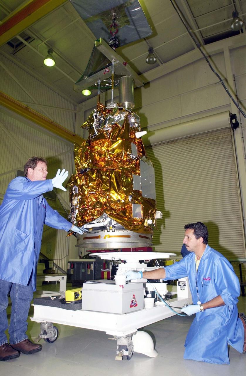 KENNEDY SPACE CENTER, FLA. - At Vandenberg Air Force Base in California, workers help guide the Demonstration of Autonomous Rendezvous Technology (DART) spacecraft onto the mobile stand below. DART was designed and built for NASA by Orbital Sciences Corporation as an advanced flight demonstrator to locate and maneuver near an orbiting satellite. DART weighs about 800 pounds and is nearly 6 feet long and 3 feet in diameter. The Orbital Sciences Pegasus XL will launch DART into a circular polar orbit of approximately 475 miles. DART is designed to demonstrate technologies required for a spacecraft to locate and rendezvous, or maneuver close to, other craft in space. Results from the DART mission will aid in the development of NASA’s Crew Exploration Vehicle and will also assist in vehicle development for crew transfer and crew rescue capability to and from the International Space Station.