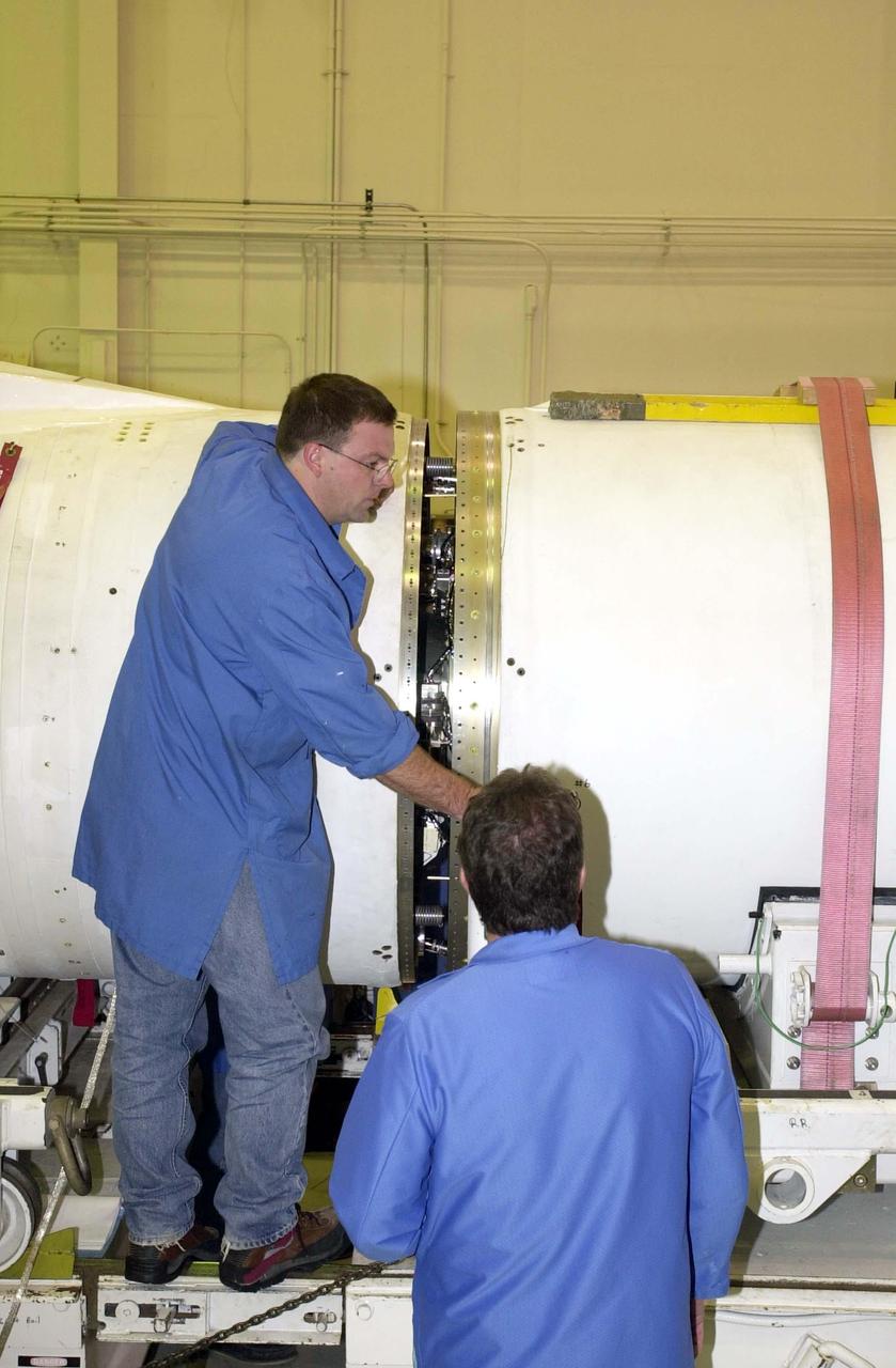 KENNEDY SPACE CENTER, FLA. - At Vandenberg Air Force Base in California, workers begin closing the gap between the second and third stages of the Orbital Sciences Pegasus XL launch vehicle that will launch the Demonstration of Autonomous Rendezvous Technology (DART) spacecraft. DART was designed and built for NASA by Orbital Sciences Corporation as an advanced flight demonstrator to locate and maneuver near an orbiting satellite. DART weighs about 800 pounds and is nearly 6 feet long and 3 feet in diameter. The Pegasus XL will launch DART into a circular polar orbit of approximately 475 miles. DART is designed to demonstrate technologies required for a spacecraft to locate and rendezvous, or maneuver close to, other craft in space. Results from the DART mission will aid in the development of NASA's Crew Exploration Vehicle and will also assist in vehicle development for crew transfer and crew rescue capability to and from the International Space Station.