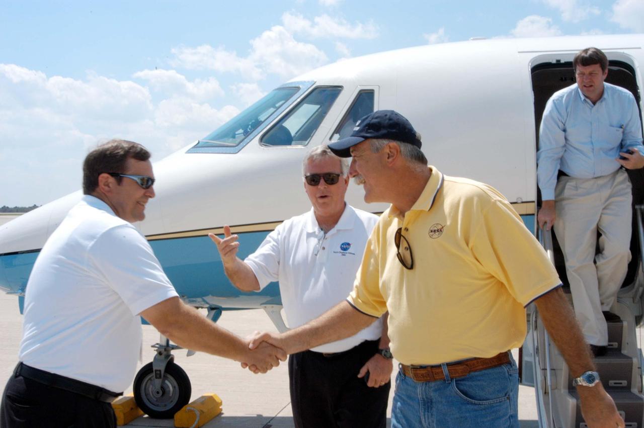 KENNEDY SPACE CENTER, FLA. -  KSC Director of Shuttle Processing Michael E. Wetmore (left) greets NASA Administrator Sean O’Keefe upon his arrival at the Shuttle Landing Facility.  O’Keefe is visiting KSC to survey the damage sustained by KSC facilities from Hurricane Frances over Labor Day weekend. Center Director Jim Kennedy (center) was also on hand to welcome O’Keefe. The Vehicle Assembly Building, Thermal Protection System Facility, and Processing Control Center all received significant damage from the storm.  Additionally, the Operations and Checkout Building, Vertical Processing Facility, Hangar AE, Hangar S and Hangar AF Small Parts Facility each received substantial damage. However, well-protected and unharmed were NASA’s three Space Shuttle orbiters -- Discovery, Atlantis and Endeavour - along with the Shuttle launch pads, all of the critical flight hardware for the orbiters and the International Space Station, and NASA’s Swift spacecraft that is awaiting launch in October.