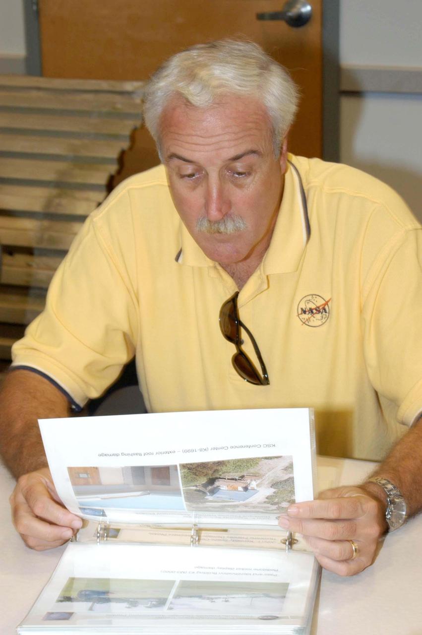 KENNEDY SPACE CENTER, FLA. -  NASA Administrator Sean O’Keefe looks at images of damaged KSC facilities in the RLV Hangar before surveying the damage sustained by KSC facilities from Hurricane Frances over Labor Day weekend.  The Vehicle Assembly Building, Thermal Protection System Facility, and Processing Control Center all received significant damage from the storm.  Additionally, the Operations and Checkout Building, Vertical Processing Facility, Hangar AE, Hangar S and Hangar AF Small Parts Facility each received substantial damage. NASA’s three Space Shuttle orbiters -- Discovery, Atlantis and Endeavour - along with the Shuttle launch pads, all of the critical flight hardware for the orbiters and the International Space Station, and NASA’s Swift spacecraft, awaiting launch in October, were well protected and unharmed.