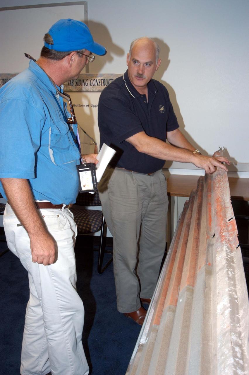 KENNEDY SPACE CENTER, FLA. -  KSC Director of the Spaceport Services Scott Kerr (left) and NASA Associate Administrator of the Space Operations Mission Directorate William Readdy examine one of the panels that was blown off the Vehicle Assembly Building.  NASA Administrator Sean O’Keefe and Readdy are visiting KSC to survey the damage sustained by KSC facilities from Hurricane Frances over Labor Day weekend. The Vehicle Assembly Building, Thermal Protection System Facility, and Processing Control Center all received significant damage from the storm.  Additionally, the Operations and Checkout Building, Vertical Processing Facility, Hangar AE, Hangar S and Hangar AF Small Parts Facility each received substantial damage. NASA’s three Space Shuttle orbiters -- Discovery, Atlantis and Endeavour - along with the Shuttle launch pads, all of the critical flight hardware for the orbiters and the International Space Station, and NASA’s Swift spacecraft, awaiting launch in October, were well protected and unharmed.