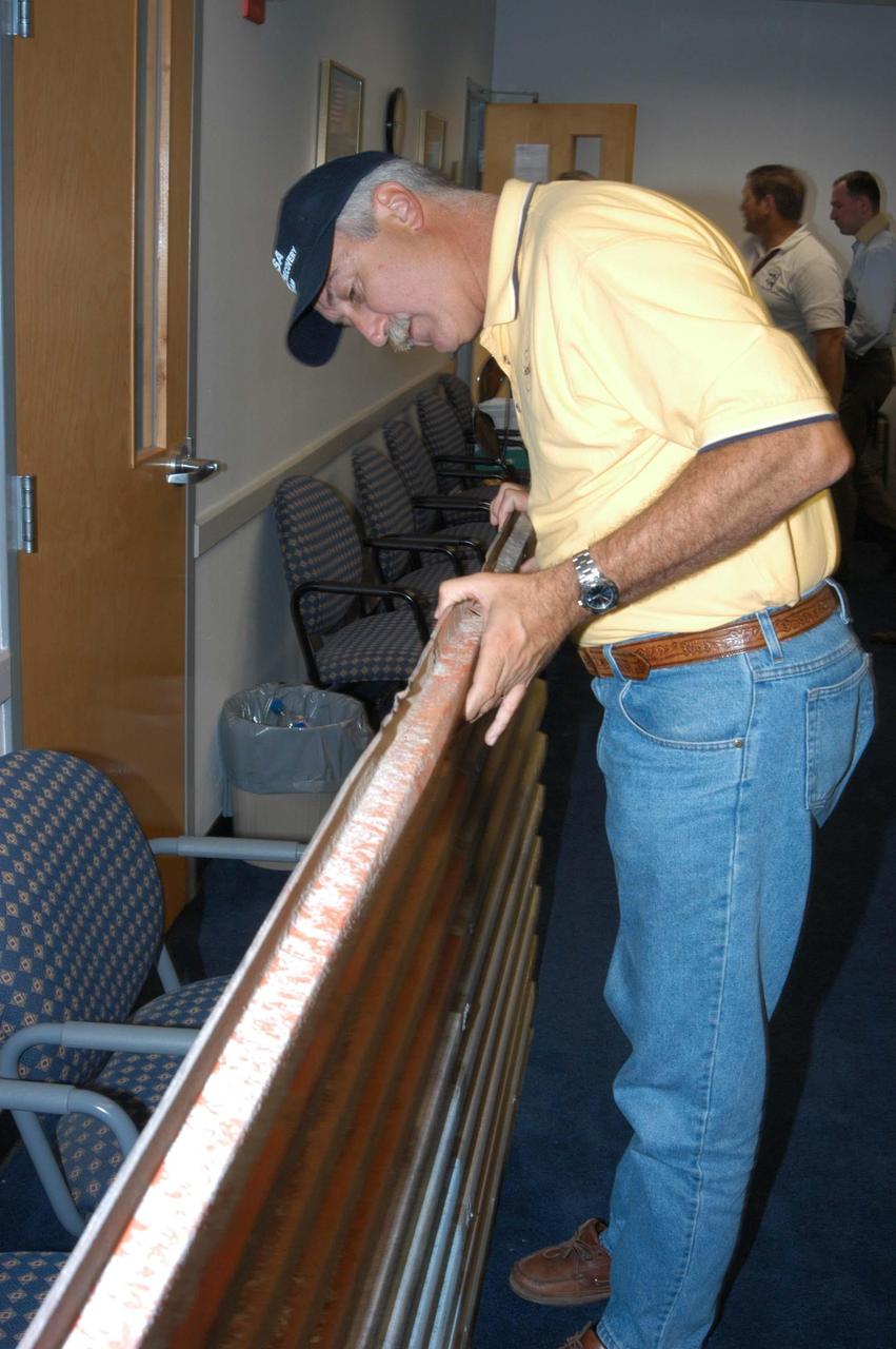 KENNEDY SPACE CENTER, FLA. -  NASA Administrator Sean O’Keefe examines one of the panels that was blown off the Vehicle Assembly Building.  O’Keefe is visiting KSC to survey the damage sustained by KSC facilities from Hurricane Frances over Labor Day weekend. The Vehicle Assembly Building, Thermal Protection System Facility, and Processing Control Center all received significant damage from the storm.  Additionally, the Operations and Checkout Building, Vertical Processing Facility, Hangar AE, Hangar S and Hangar AF Small Parts Facility each received substantial damage. NASA’s three Space Shuttle orbiters -- Discovery, Atlantis and Endeavour - along with the Shuttle launch pads, all of the critical flight hardware for the orbiters and the International Space Station, and NASA’s Swift spacecraft, awaiting launch in October, were well protected and unharmed.