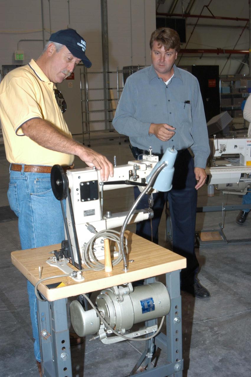 KENNEDY SPACE CENTER, FLA. -  NASA Administrator Sean O’Keefe looks at equipment moved from the Thermal Protection System Facility to the RLV Hangar.  AT right is Martin Wilson, manager of TPS operations for United Space Alliance.  O’Keefe and NASA Associate Administrator of  Space Operations Mission Directorate William Readdy are visiting KSC to survey the damage sustained by KSC facilities from Hurricane Frances. The Thermal Protection System Facility (TPSF), which creates the TPS tiles, blankets and all the internal thermal control systems for the Space Shuttles, is almost totally unserviceable at this time after losing approximately 35 percent of its roof in the storm, which blew across Central Florida Sept. 4-5. Undamaged equipment was removed from the TPSF and stored in the hangar. The Labor Day storm also caused significant damage to the Vehicle Assembly Building and Processing Control Center.  Additionally, the Operations and Checkout Building, Vertical Processing Facility, Hangar AE, Hangar S and Hangar AF Small Parts Facility each received substantial damage.  However, well-protected and unharmed were NASA’s three Space Shuttle orbiters -- Discovery, Atlantis and Endeavour - along with the Shuttle launch pads, all of the critical flight hardware for the orbiters and the International Space Station, and NASA’s Swift spacecraft that is awaiting launch in October.