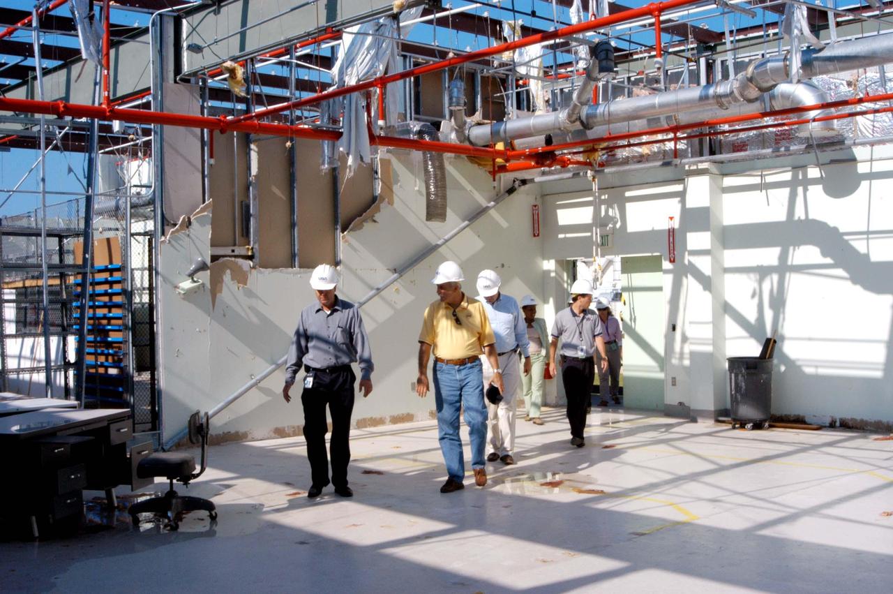 KENNEDY SPACE CENTER, FLA. -  Martin Wilson (far left), manager of Thermal Protection System (TPS) operations for United Space Alliance (USA), leads NASA Administrator Sean O’Keefe (second from left) on a tour of the hurricane-ravaged Thermal Protection System Facility.  The TPSF, which creates the TPS tiles, blankets and all the internal thermal control systems for the Space Shuttles, is almost totally unserviceable at this time after losing approximately 35 percent of its roof in the storm, which blew across Central Florida Sept. 4-5. Undamaged equipment was removed from the TPSF and stored in the RLV hangar. O’Keefe and NASA Associate Administrator of  Space Operations Mission Directorate William Readdy are visiting KSC to survey the damage sustained by KSC facilities from the hurricane.  The Labor Day storm also caused significant damage to the Vehicle Assembly Building and Processing Control Center.  Additionally, the Operations and Checkout Building, Vertical Processing Facility, Hangar AE, Hangar S and Hangar AF Small Parts Facility each received substantial damage. However, well-protected and unharmed were NASA’s three Space Shuttle orbiters - Discovery, Atlantis and Endeavour - along with the Shuttle launch pads, all of the critical flight hardware for the orbiters and the International Space Station, and NASA’s Swift spacecraft that is awaiting launch in October.