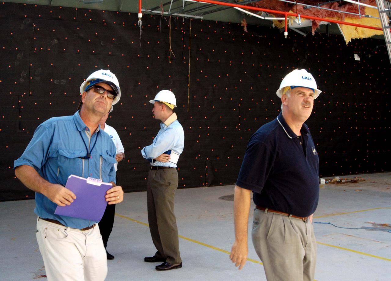 KENNEDY SPACE CENTER, FLA. -  Looking at damage inside the hurricane-ravaged Thermal Protection System Facility are KSC Director of Spaceport Services Scott Kerr (left) and NASA Associate Administrator of  Space Operations Mission Directorate William Readdy (right).  The TPSF, which creates the TPS tiles, blankets and all the internal thermal control systems for the Space Shuttles, is almost totally unserviceable at this time after losing approximately 35 percent of its roof during Hurricane Frances, which blew across Central Florida Sept. 4-5.  Readdy and NASA Administrator Sean O’Keefe are visiting KSC to survey the damage sustained by KSC facilities from the hurricane.  The Labor Day storm also caused significant damage to the Vehicle Assembly Building and Processing Control Center.  Additionally, the Operations and Checkout Building, Vertical Processing Facility, Hangar AE, Hangar S and Hangar AF Small Parts Facility each received substantial damage. However, well-protected and unharmed were NASA’s three Space Shuttle orbiters - Discovery, Atlantis and Endeavour - along with the Shuttle launch pads, all of the critical flight hardware for the orbiters and the International Space Station, and NASA’s Swift spacecraft that is awaiting launch in October.