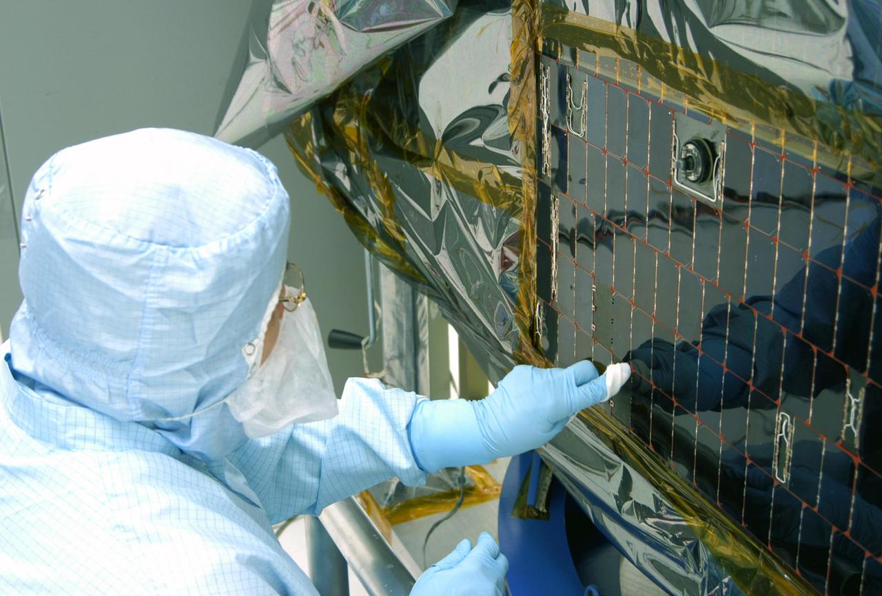 KENNEDY SPACE CENTER, FLA. -  In the clean room at NASA’s Hangar AE on Cape Canaveral Air Force Station (CCAFS), a Spectrolab technician, Anna Herrera,  points to an area on the Swift spacecraft’s solar array where cells will be removed and replaced.  Swift is a first-of-its-kind, multi-wavelength observatory dedicated to the study of gamma-ray burst (GRB) science. Its three instruments will work together to observe GRBs and afterglows in the gamma-ray, X-ray, ultraviolet and optical wavebands. The main mission objectives for Swift are to determine the origin of gamma-ray bursts, classify gamma-ray bursts and search for new types, determine how the blast wave evolves and interacts with the surroundings, use gamma-ray bursts to study the early universe and perform the first sensitive hard X-ray survey of the sky.  Swift is scheduled to launch Oct. 26 from Launch Pad 17-A, CCAFS, on a Boeing Delta 7320 rocket.