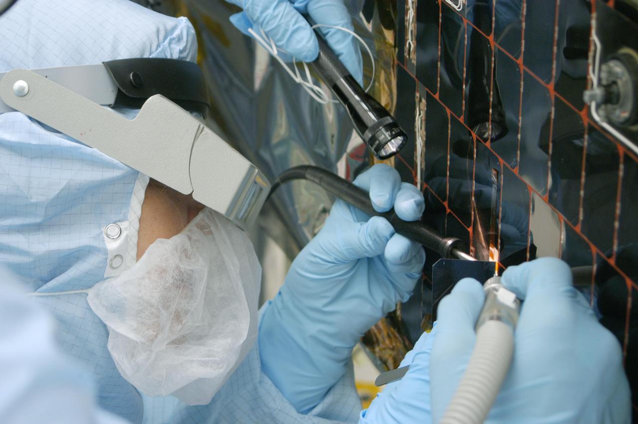 KENNEDY SPACE CENTER, FLA. -  In the clean room at NASA’s Hangar AE on Cape Canaveral Air Force Station (CCAFS), a Spectrolab technician, Anna Herrera,  removes one of the solar cells that will be replaced on the Swift spacecraft’s solar array.  Swift is a first-of-its-kind, multi-wavelength observatory dedicated to the study of gamma-ray burst (GRB) science. Its three instruments will work together to observe GRBs and afterglows in the gamma-ray, X-ray, ultraviolet and optical wavebands. The main mission objectives for Swift are to determine the origin of gamma-ray bursts, classify gamma-ray bursts and search for new types, determine how the blast wave evolves and interacts with the surroundings, use gamma-ray bursts to study the early universe and perform the first sensitive hard X-ray survey of the sky.  Swift is scheduled to launch Oct. 26 from Launch Pad 17-A, CCAFS, on a Boeing Delta 7320 rocket.