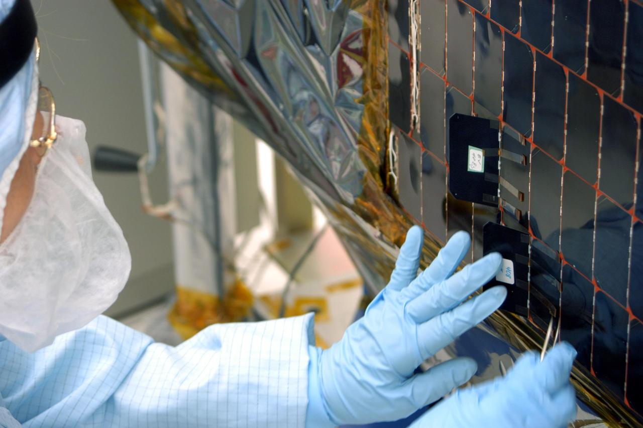 KENNEDY SPACE CENTER, FLA. -  In the clean room at NASA’s Hangar AE on Cape Canaveral Air Force Station (CCAFS), a Spectrolab technician, Anna Herrera,  places a new solar cell on the Swift spacecraft’s solar array.  Swift is a first-of-its-kind, multi-wavelength observatory dedicated to the study of gamma-ray burst (GRB) science. Its three instruments will work together to observe GRBs and afterglows in the gamma-ray, X-ray, ultraviolet and optical wavebands. The main mission objectives for Swift are to determine the origin of gamma-ray bursts, classify gamma-ray bursts and search for new types, determine how the blast wave evolves and interacts with the surroundings, use gamma-ray bursts to study the early universe and perform the first sensitive hard X-ray survey of the sky.  Swift is scheduled to launch Oct. 26 from Launch Pad 17-A, CCAFS, on a Boeing Delta 7320 rocket.