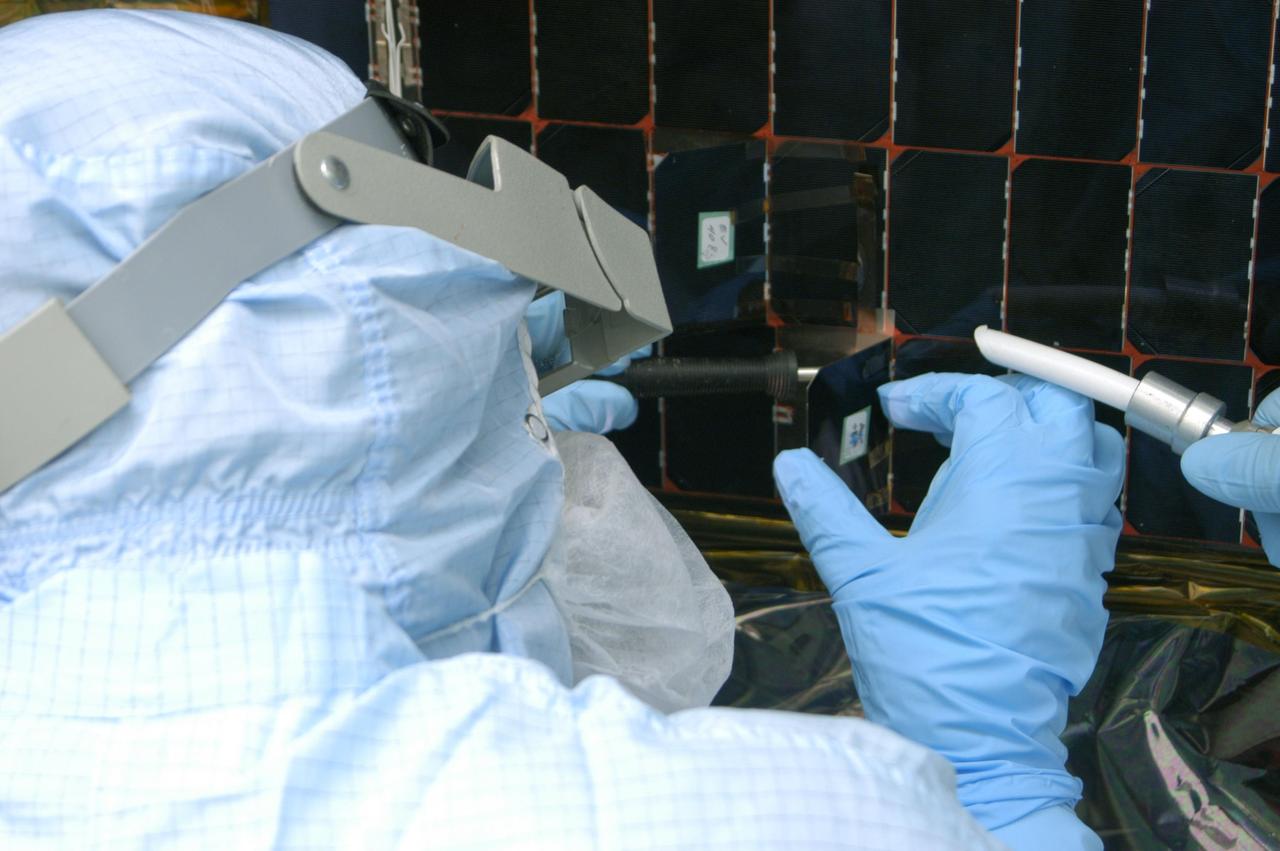 KENNEDY SPACE CENTER, FLA. -  In the clean room at NASA’s Hangar AE on Cape Canaveral Air Force Station (CCAFS), a Spectrolab technician, Anna Herrera,  places a new solar cell on the Swift spacecraft’s solar array.  Swift is a first-of-its-kind, multi-wavelength observatory dedicated to the study of gamma-ray burst (GRB) science. Its three instruments will work together to observe GRBs and afterglows in the gamma-ray, X-ray, ultraviolet and optical wavebands. The main mission objectives for Swift are to determine the origin of gamma-ray bursts, classify gamma-ray bursts and search for new types, determine how the blast wave evolves and interacts with the surroundings, use gamma-ray bursts to study the early universe and perform the first sensitive hard X-ray survey of the sky.  Swift is scheduled to launch Oct. 26 from Launch Pad 17-A, CCAFS, on a Boeing Delta 7320 rocket.