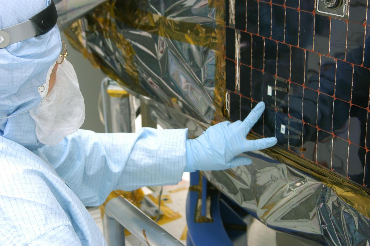 KENNEDY SPACE CENTER, FLA. -  In the clean room at NASA’s Hangar AE on Cape Canaveral Air Force Station (CCAFS), a Spectrolab technician, Anna Herrera,  points to the two new solar cells removed and replaced on the Swift spacecraft’s solar array.  Swift is a first-of-its-kind, multi-wavelength observatory dedicated to the study of gamma-ray burst (GRB) science. Its three instruments will work together to observe GRBs and afterglows in the gamma-ray, X-ray, ultraviolet and optical wavebands. The main mission objectives for Swift are to determine the origin of gamma-ray bursts, classify gamma-ray bursts and search for new types, determine how the blast wave evolves and interacts with the surroundings, use gamma-ray bursts to study the early universe and perform the first sensitive hard X-ray survey of the sky.  Swift is scheduled to launch Oct. 26 from Launch Pad 17-A, CCAFS, on a Boeing Delta 7320 rocket.