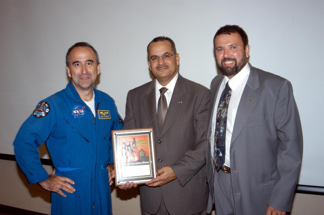 KENNEDY SPACE CENTER, FLA. -  Astronaut Fernando Caldeiro (left) and Joseph Tellado (right) present a memento of appreciation to Charles A. Gambaro (center), NASA KSC engineering lead and Combat Engineering Group commander, who recently returned from Operation Iraqi Freedom.  Gambaro was the guest speaker at KSC’s  annual Hispanic American Heritage luncheon.  The theme was “Hispanic Americans Making a Difference.”  Caldeiro was born in Buenos Aires, Argentina.  Tellado was co-chair of the event hosted by the Hispanic Employment Program Working Group. The annual event helps employees reflect on the extensive contributions Hispanics have made to KSC, NASA and the nation.