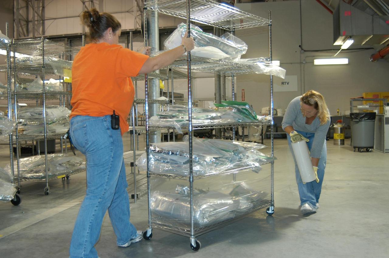 KENNEDY SPACE CENTER, FLA. - In the Reusable Launch Vehicle (RLV) Hangar, workers begin wrapping racks of equipment in preparation for the arrival of Hurricane Jeanne, expected to impact Central Florida Sunday. This is the fourth hurricane in 45 days to make landfall somewhere in the state.  The Thermal Protection System (TPS) Facility suffered extensive damage from Hurricane Frances, causing the relocation of equipment to the RLV.