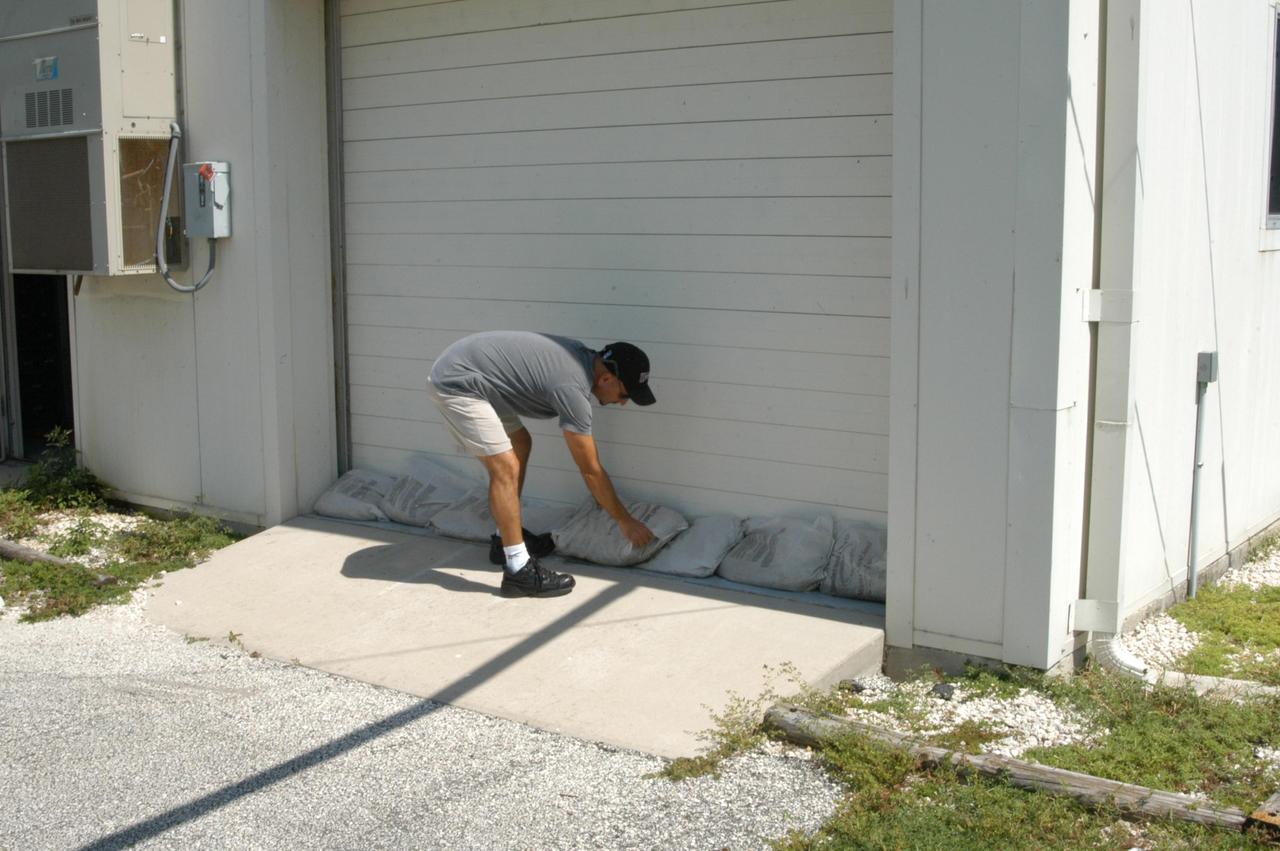 KENNEDY SPACE CENTER, FLA. - A worker places sandbags at the bottom of the door into the Reusable Launch Vehicle Support Complex in preparation for the arrival of Hurricane Jeanne, expected to impact Central Florida Sunday. This is the fourth hurricane in 45 days to make landfall somewhere in the state.
