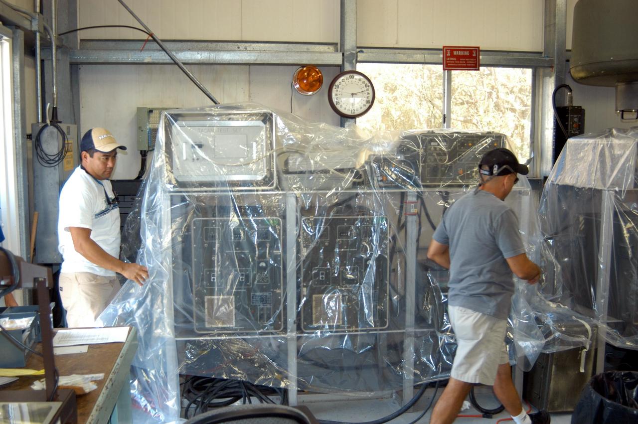 KENNEDY SPACE CENTER, FLA. - Workers place plastic sheets over racks of equipment in the Reusable Launch Vehicle Support Complex in preparation for the arrival of Hurricane Jeanne, expected to impact Central Florida Sunday. This is the fourth hurricane in 45 days to make landfall somewhere in the state.