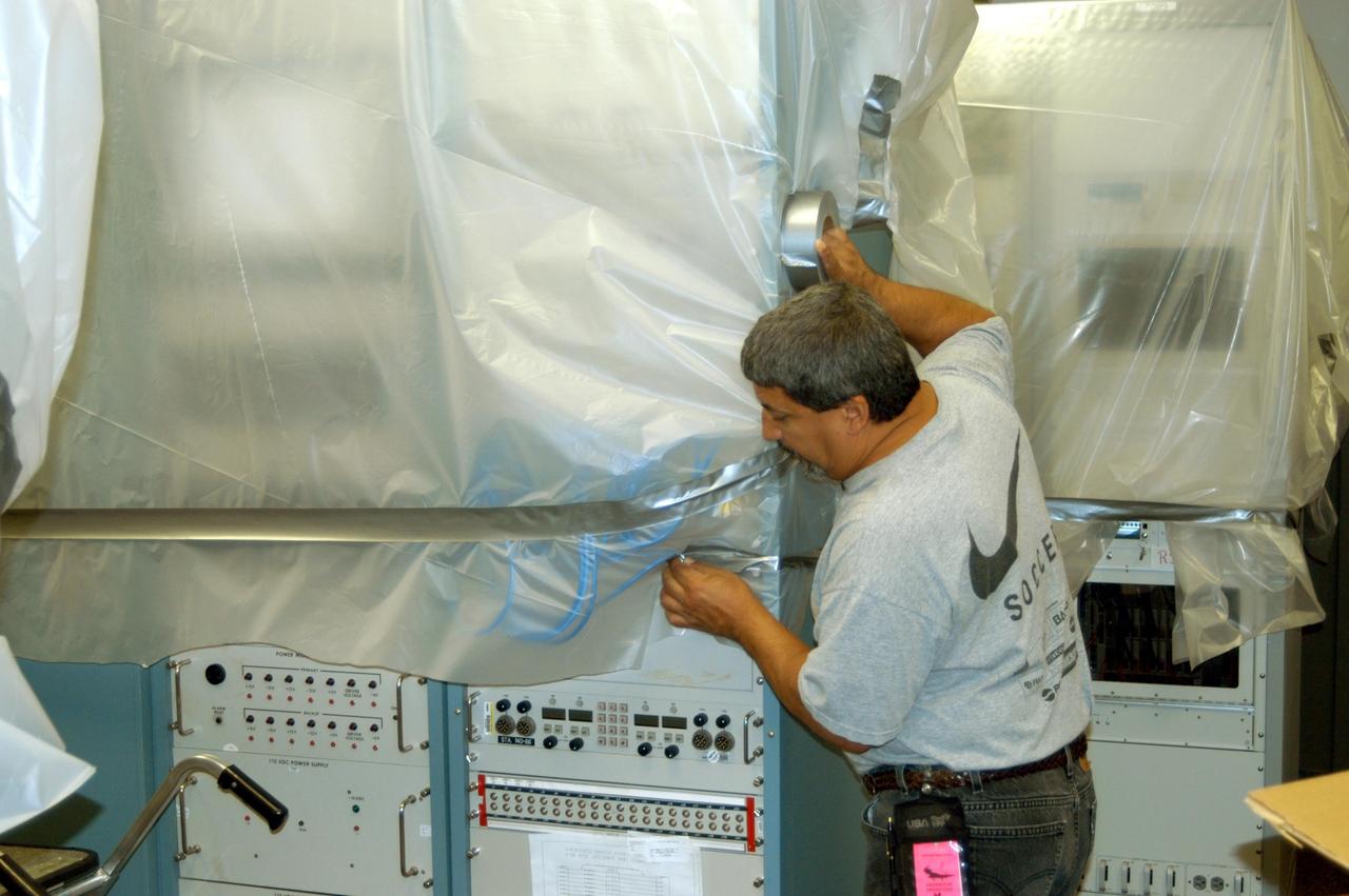 KENNEDY SPACE CENTER, FLA. - A worker covers large pieces of equipment in the Processing Control Center in the Launch Complex 39 Area in preparation for the arrival of Hurricane Jeanne, expected to impact Central Florida Sunday. This is the fourth hurricane in 45 days to make landfall somewhere in the state.