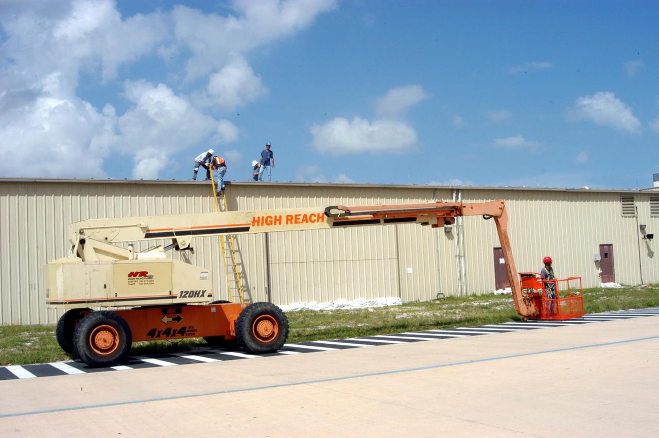 KENNEDY SPACE CENTER, FLA. - Workers attempt to secure the roof of the Tile Shop in the Thermal Protection System Facility (TPSF) in preparation for Hurricane Jeanne, which is expected to impact Central Florida Sunday.  The TPSF, which creates the TPS tiles, blankets and all the internal thermal control systems for the Space Shuttles, lost approximately 35 percent of its roof during Hurricane Frances, which blew across Central Florida Sept. 4.  Jeanne is the fourth hurricane in 45 days to make landfall somewhere in the state.