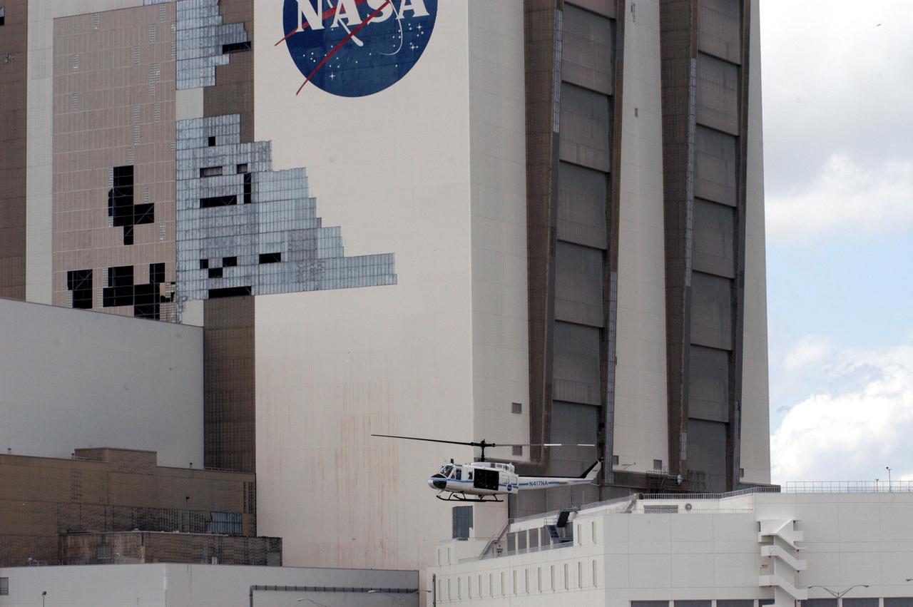 KENNEDY SPACE CENTER, FLA. - A helicopter moves past the Vehicle Assembly Building at KSC following the category 3 Hurricane Jeanne. The storm barreled through Central Florida Sept. 25-26 from the southeast. The VAB had lost 850 panels from the south wall during Hurricane Frances. Twenty-five additional panels were pulled off the east wall by the winds from Jeanne. This was the fourth hurricane in 6 weeks to batter the state.